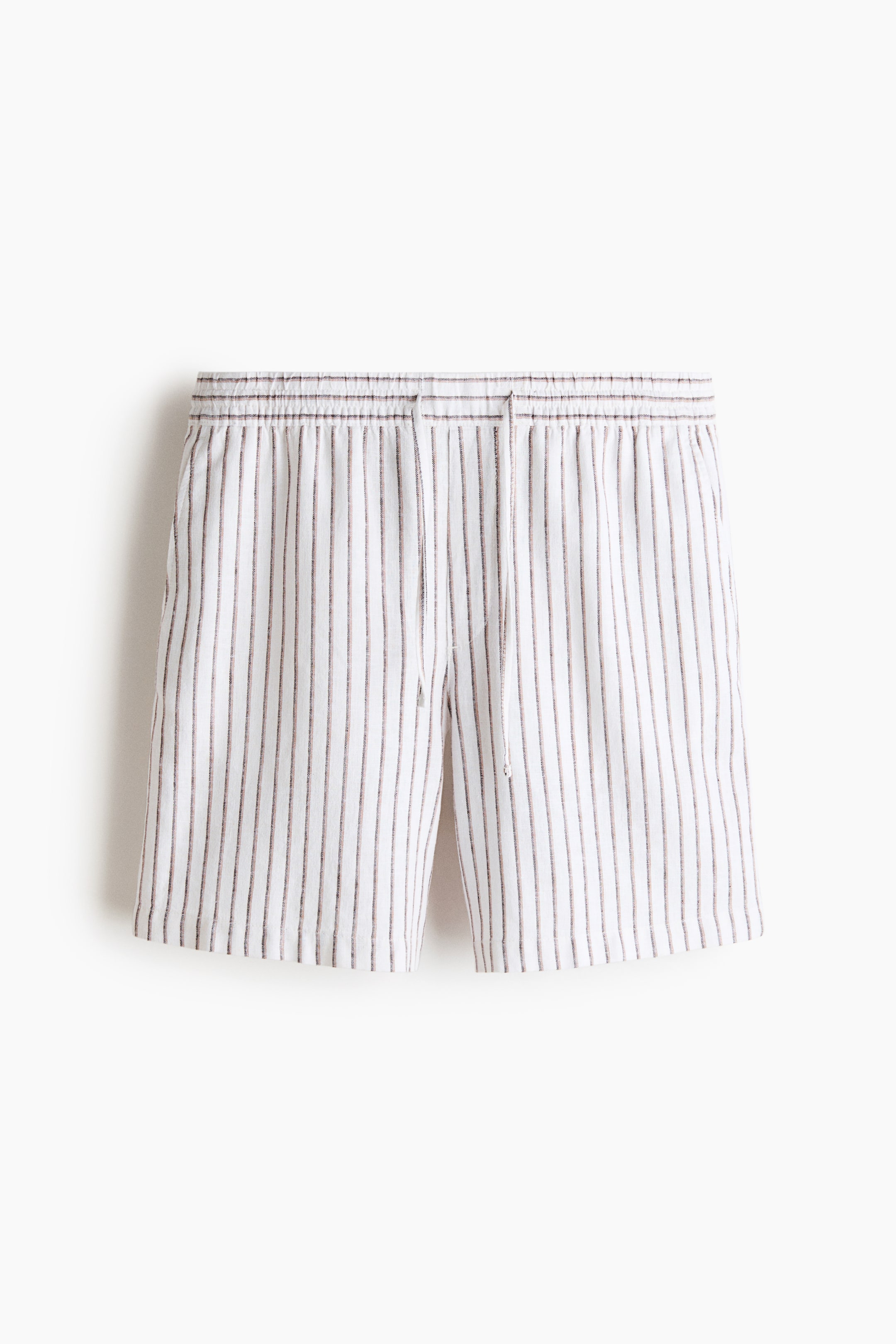 Ampliar la imagen: Los shorts presentan una tela blanca con finas rayas verticales en color marrón oscuro, una cintura elástica, un cordón blanco y discretos bolsillos laterales.