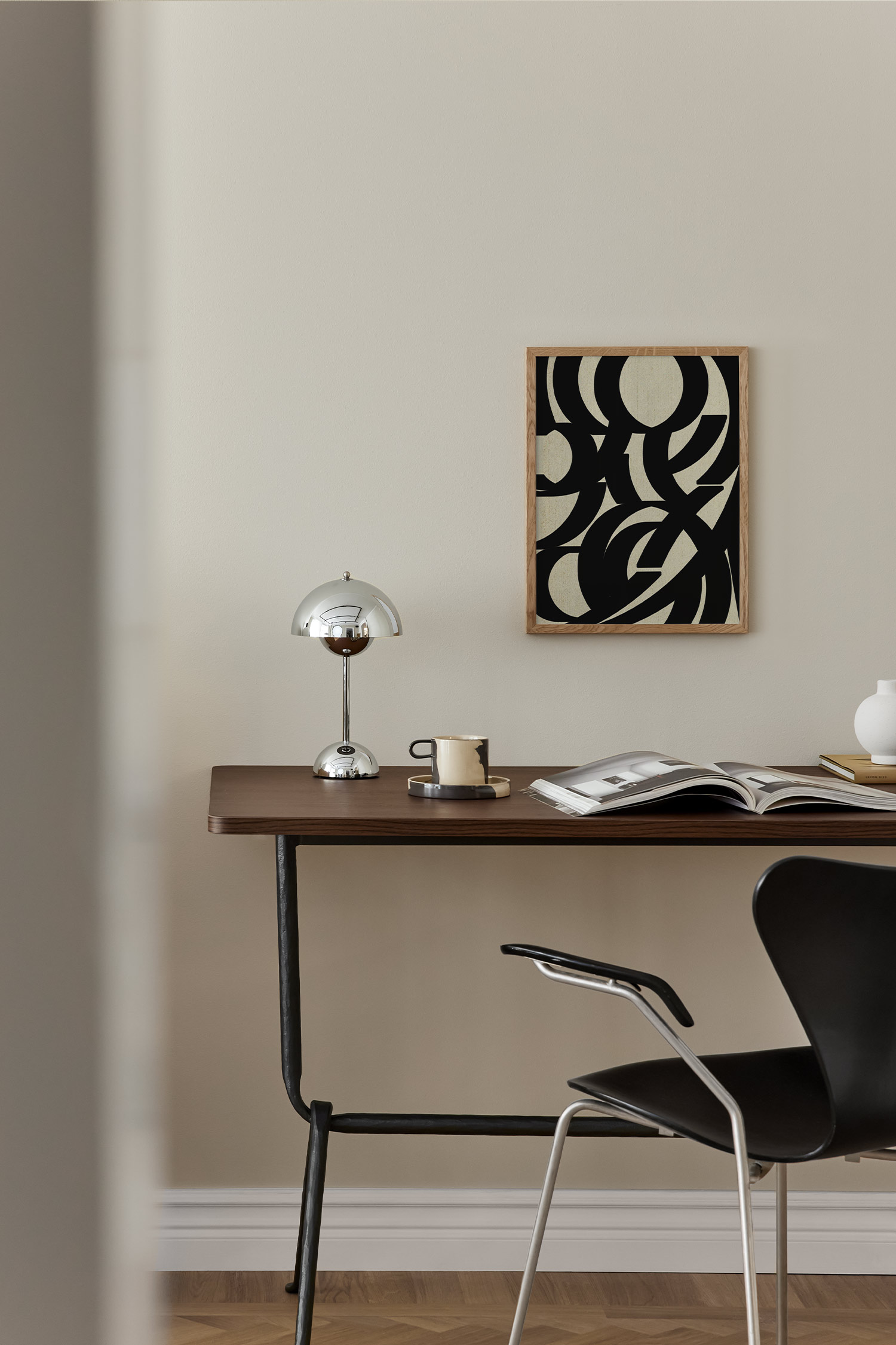 A rectangular art print displays a front view of an abstract composition featuring bold, black overlapping curved and linear shapes. The graphic elements contrast against a textured, light beige background to create a dynamic visual pattern.