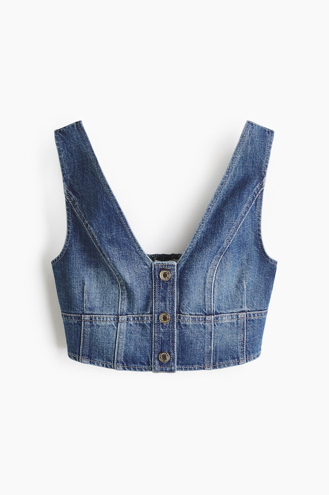 Een vervaagd blauw denim gilet presenteert een diepe V-hals. Het is voorzien van een voorste knopenlijst met vier metalen knopen en zichtbare contraststiksels die de aansluitende verticale en horizontale naden omlijnen. - 1