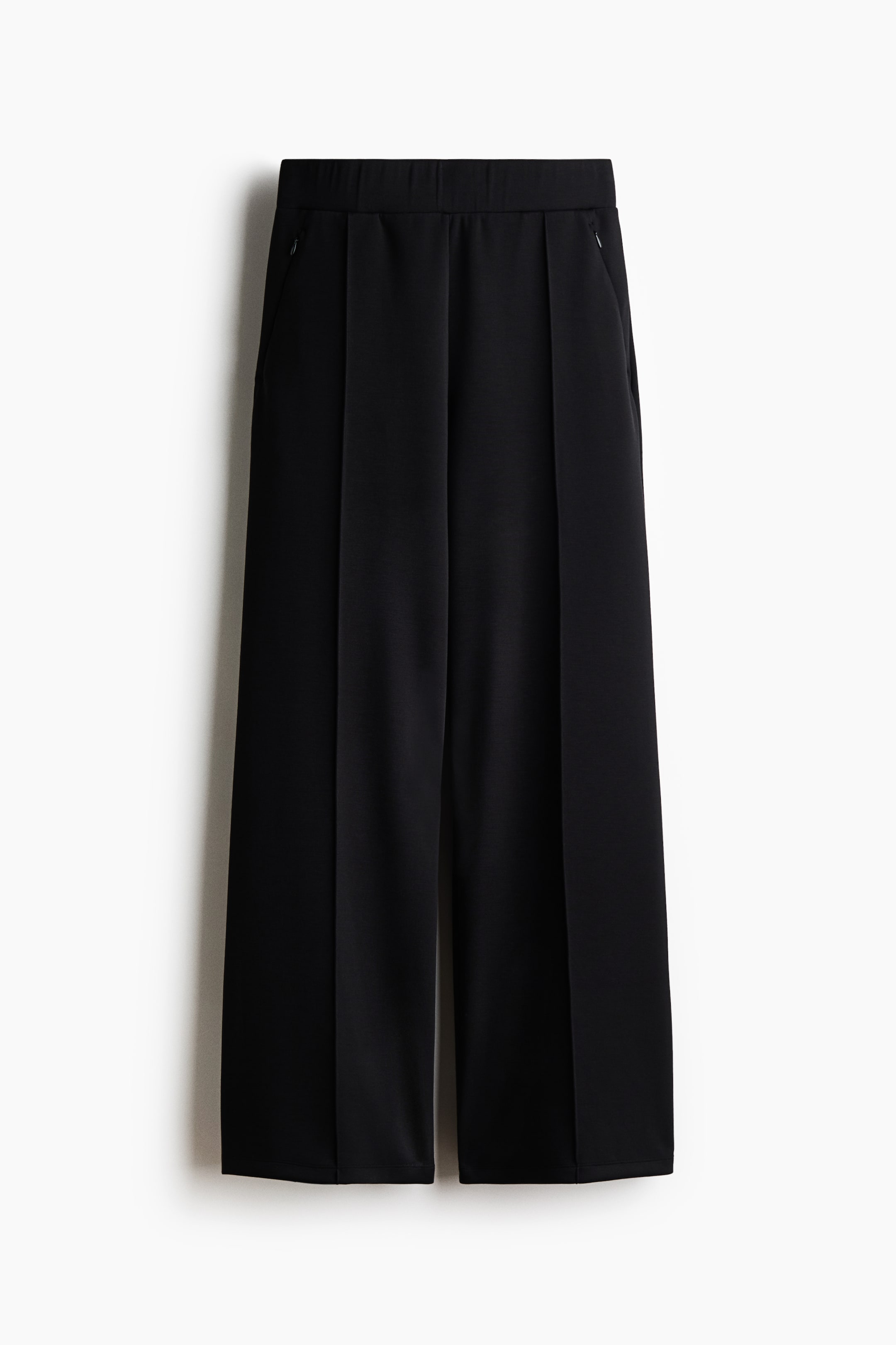 Grösseres Bild ansehen: Die schwarzen Cooling Relaxed Fit Wide Pants hängen in frontaler Ansicht und zeigen eine entspannte, weit geschnittene Silhouette mit elastischem Bund. Die Hose weist markante, mittige Bügelfalten entlang jedes Beins auf und verfügt über dezente Seitentaschen mit Reissverschluss.