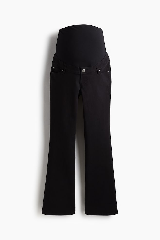 Black maternity pants are presented from the front, featuring an over-the-belly panel and a single button closure at the waist. The pants are styled with front pockets and are flaring slightly at the ankle, forming a bootcut silhouette. - 1