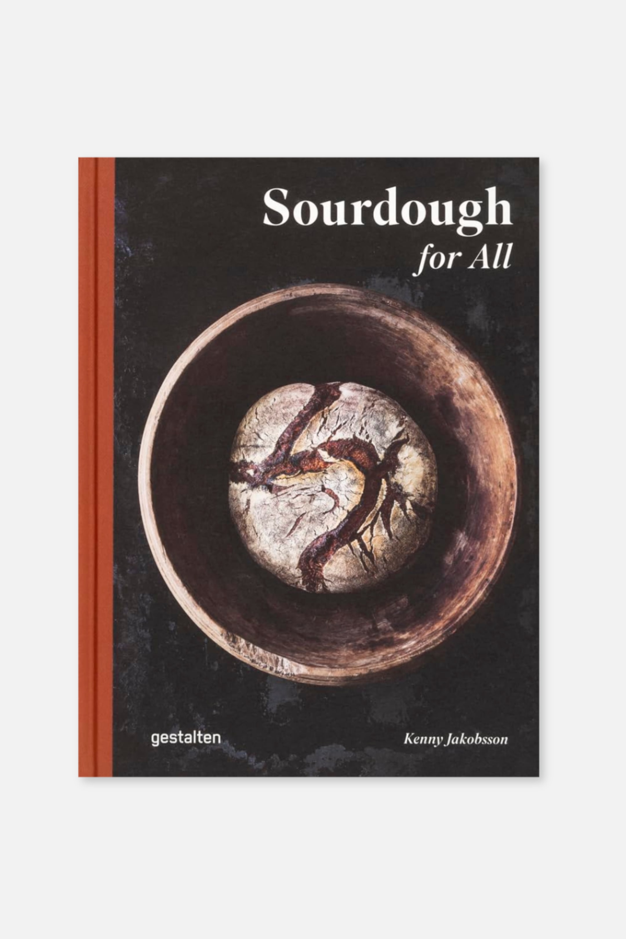 Agrandir l'image: La couverture du livre, orientée vers l'avant, présente une tranche rouge sur son bord gauche et une couverture avant noire. L'image de la couverture représente un pain au levain rond, cuit au four, avec des incisions profondes, reposant à l'intérieur d'un bol en bois. Le titre "Sourdough for All" est imprimé en blanc en haut, tandis que "gestalten" et "Kenny Jakobsson" sont visibles en blanc en bas.