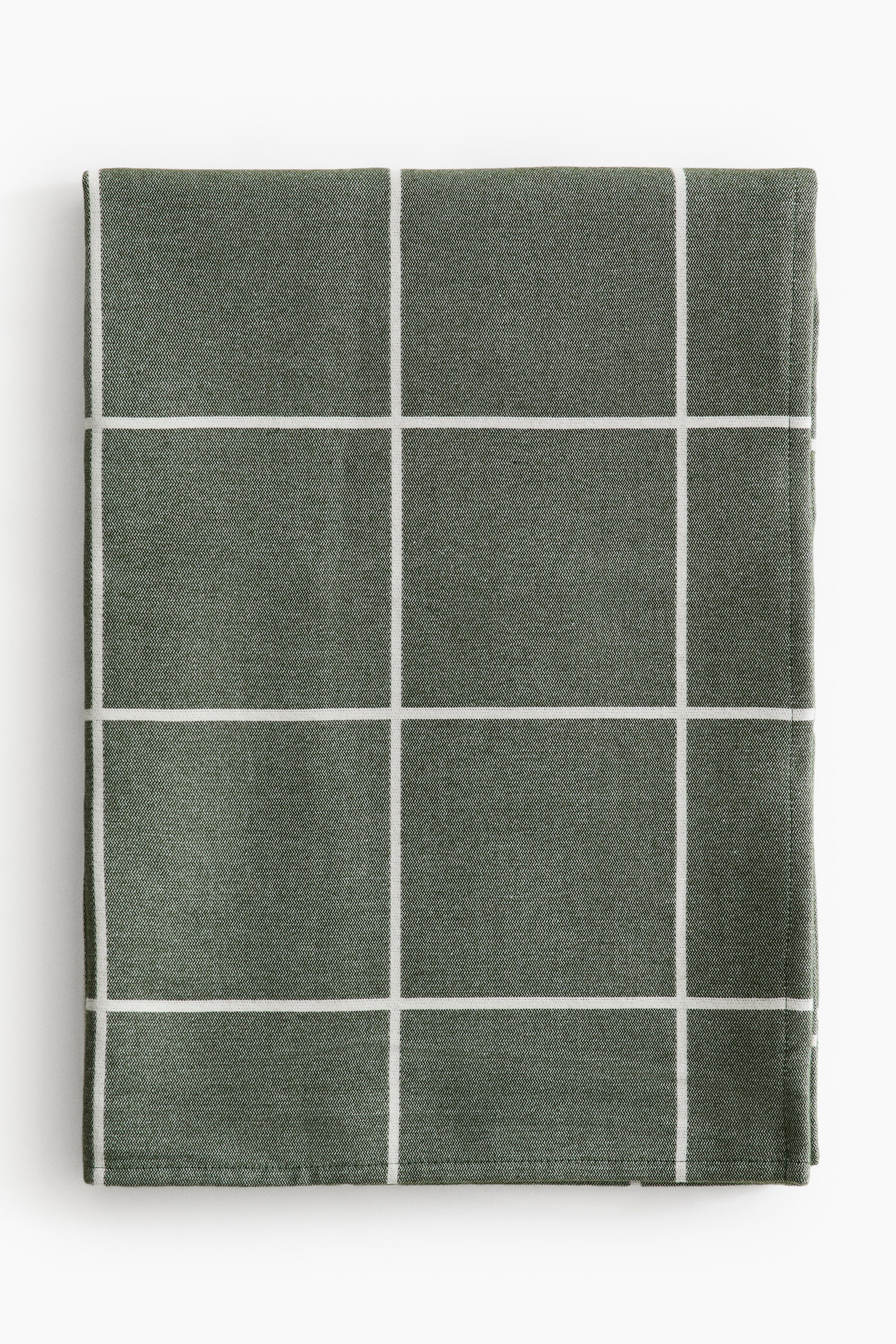 View larger image: A reversible bed throw is presented folded flat and facing front, displaying a dark green soft-weave fabric with a contrasting white grid pattern.