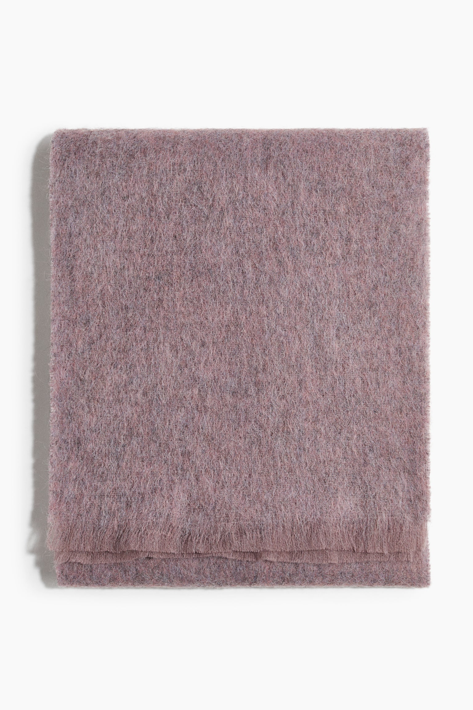 A folded dusty pink scarf is lying flat in a front-facing view, showcasing its fuzzy, brushed texture and fringed edges along the bottom fold.