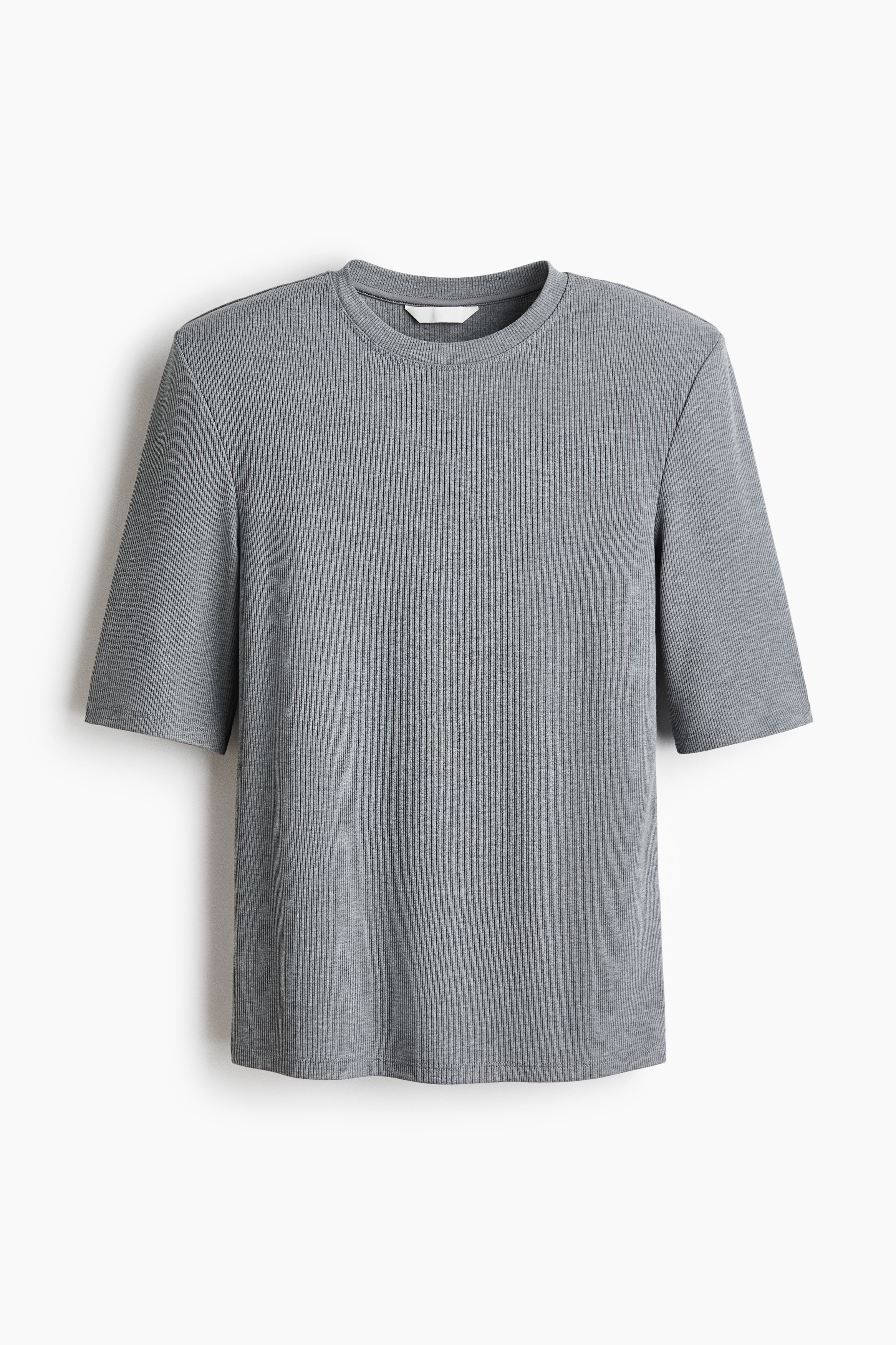 A gray fitted tee in ribbed jersey, featuring a round neckline and structured shoulder pads, is being worn by the model. The tee is styled tucked into high-waisted black jeans with a black belt.