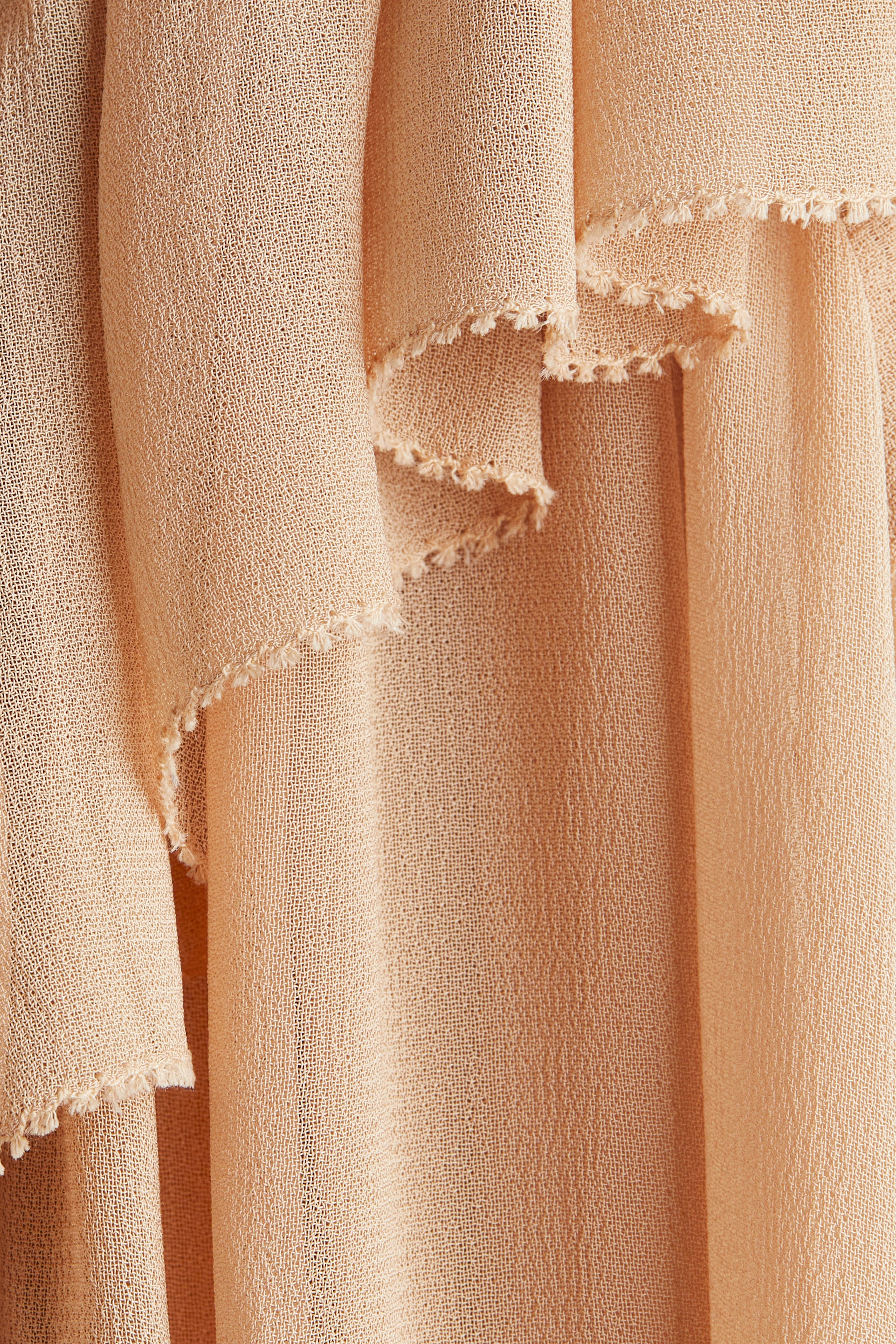 View larger image: A sleeveless blouse is showcasing a wide, V-shaped flounce on its front, detailed with a visible frill-trimmed edge. The blouse is crafted from a sheer, textured viscose weave.