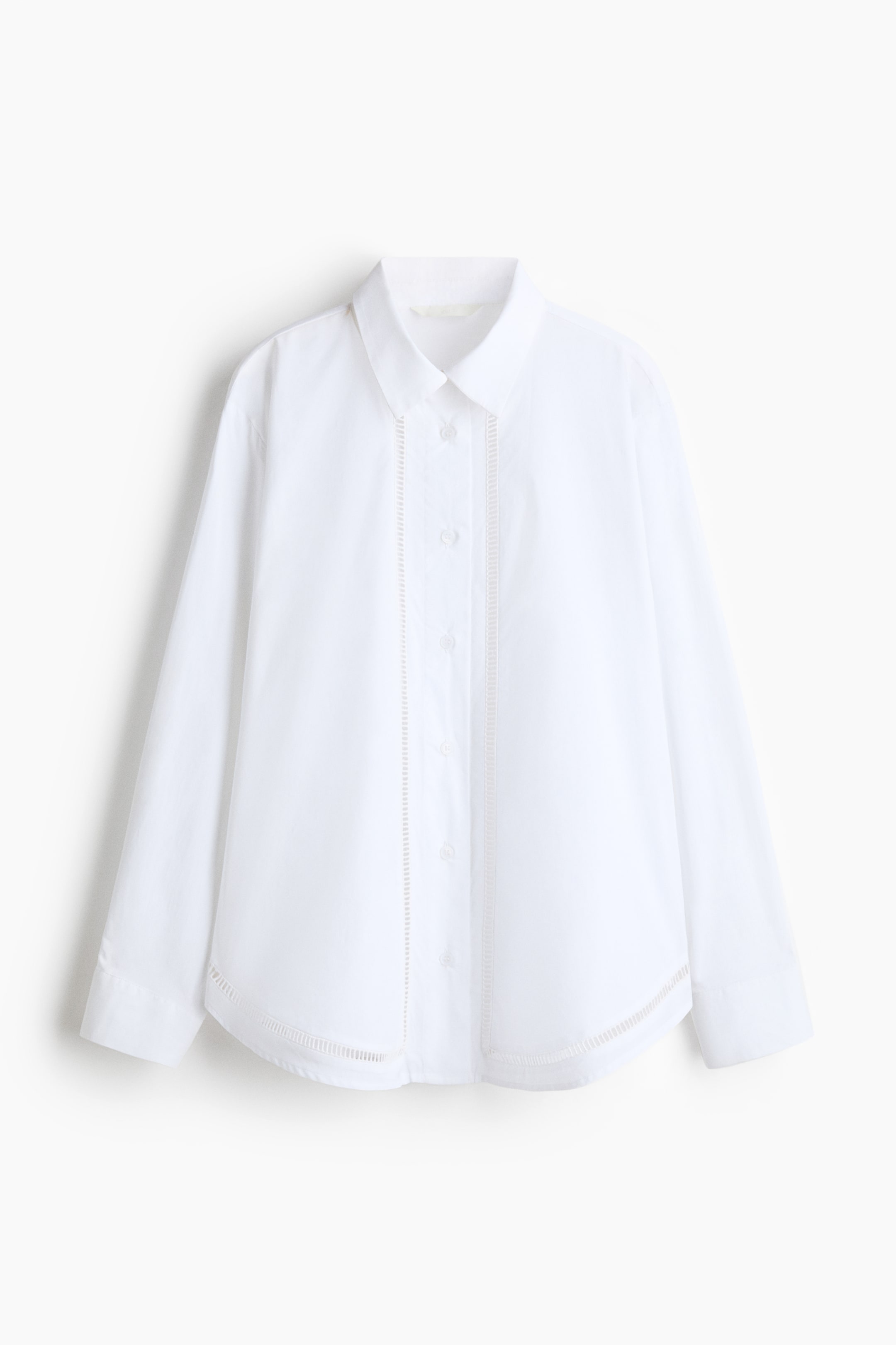 View larger image: A white button-up shirt is displayed from the front, featuring a pointed collar and long sleeves. It shows vertical ladder-stitch detailing on either side of the button placket and a horizontal ladder-stitch detail above the curved hem.