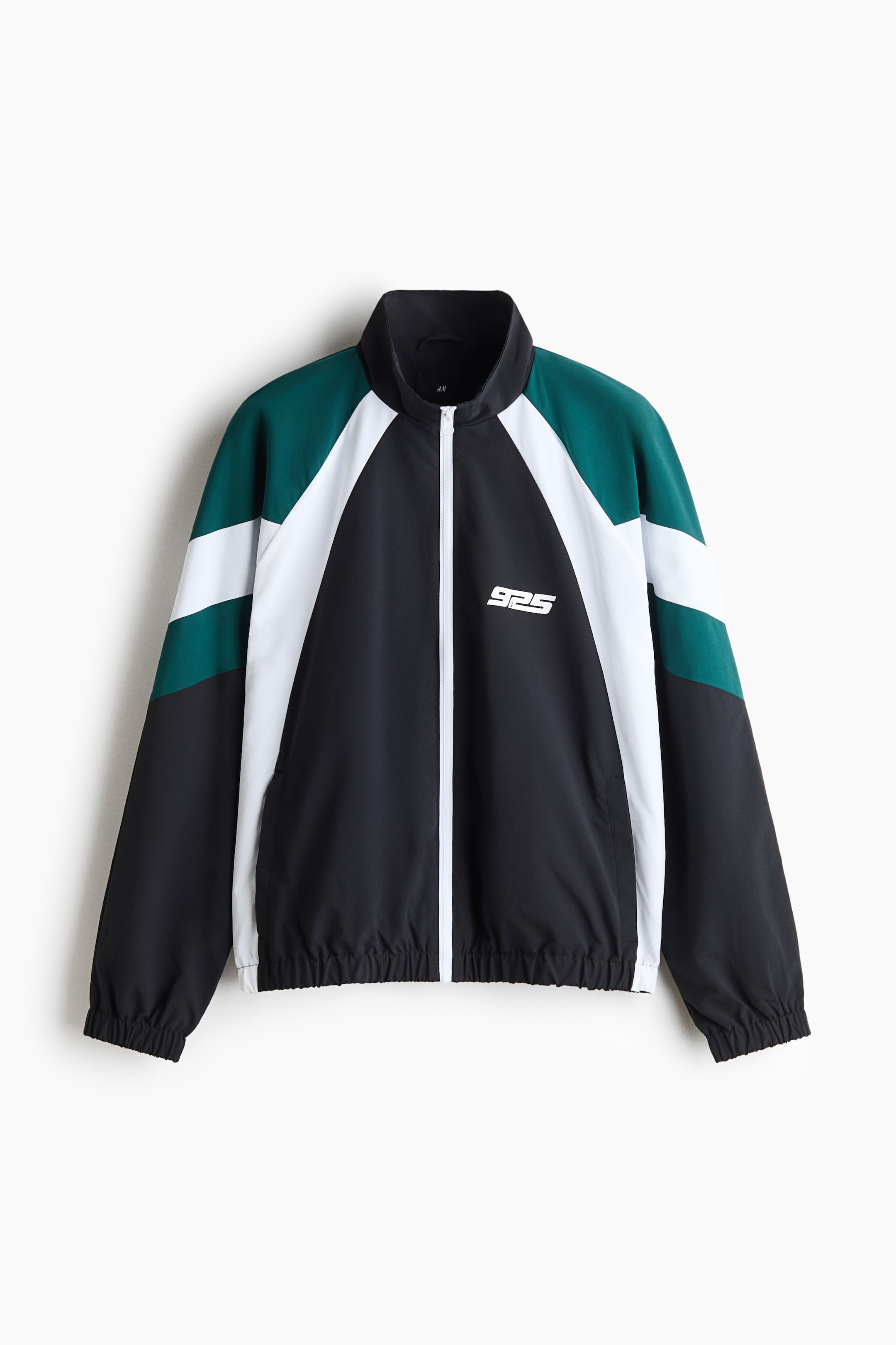 View larger image: A color-blocked track jacket is shown from the front, featuring a black, dark green, and white paneled design with a stand collar and a white front zipper. The jacket has long raglan sleeves with elastic cuffs, an elastic hem, and a small white graphic logo printed on the left chest.