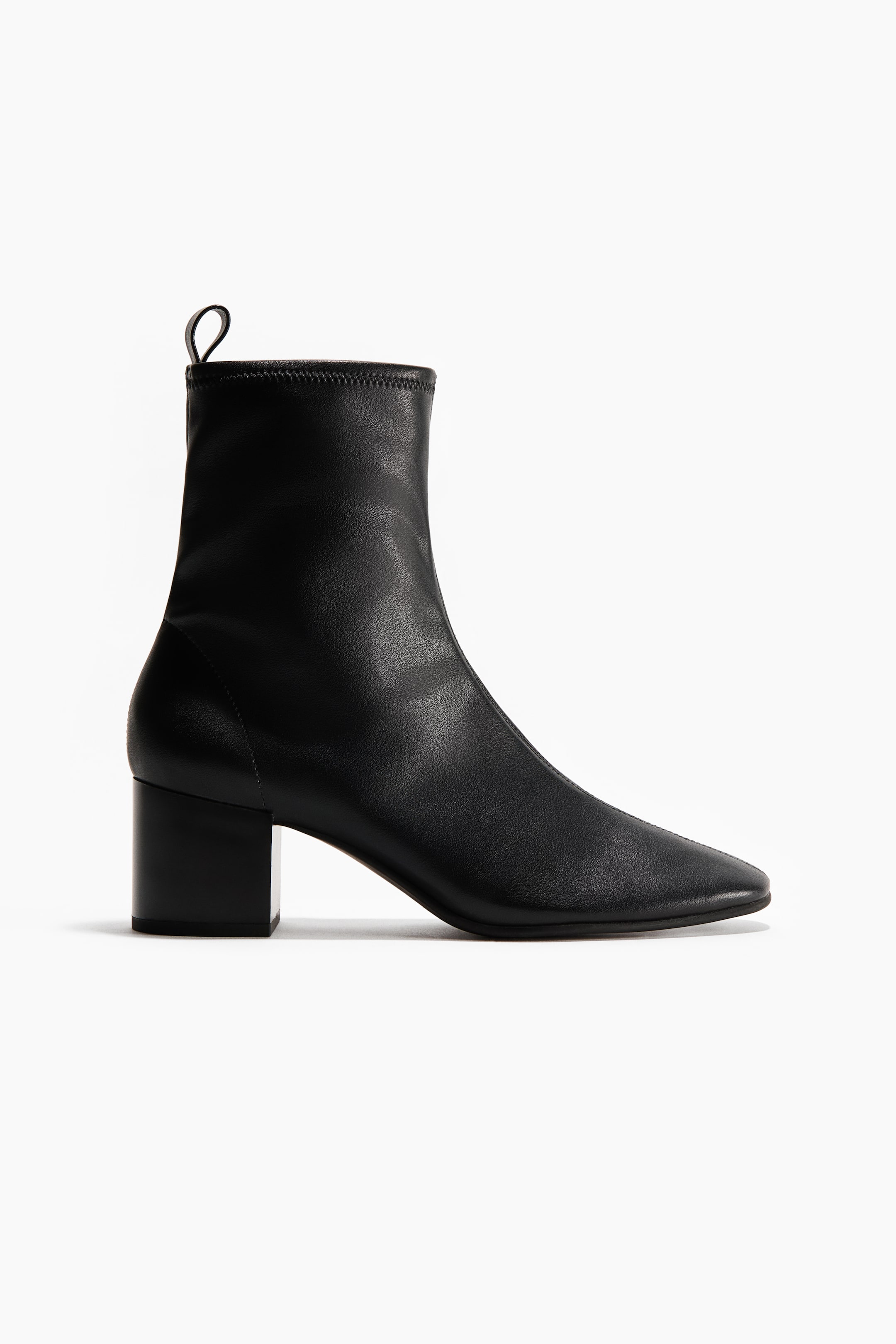 Agrandir l'image: Une botte-chaussette noire est orientée vers la droite, affichant une tige lisse avec un bout légèrement pointu et un talon bloc de hauteur moyenne. Elle est dotée d'une petite languette à l'arrière de l'ouverture de la cheville.