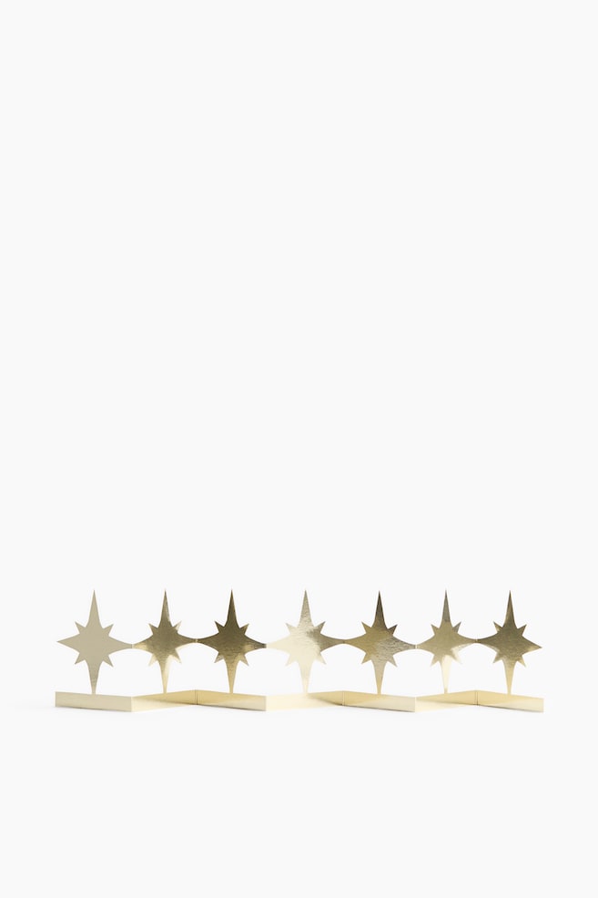 A metallic gold starburst border stands upright, featuring a row of seven connected eight-pointed stars. The product is facing forward, showcasing its accordion-folded base, which creates a self-standing, zigzag structure. - 1