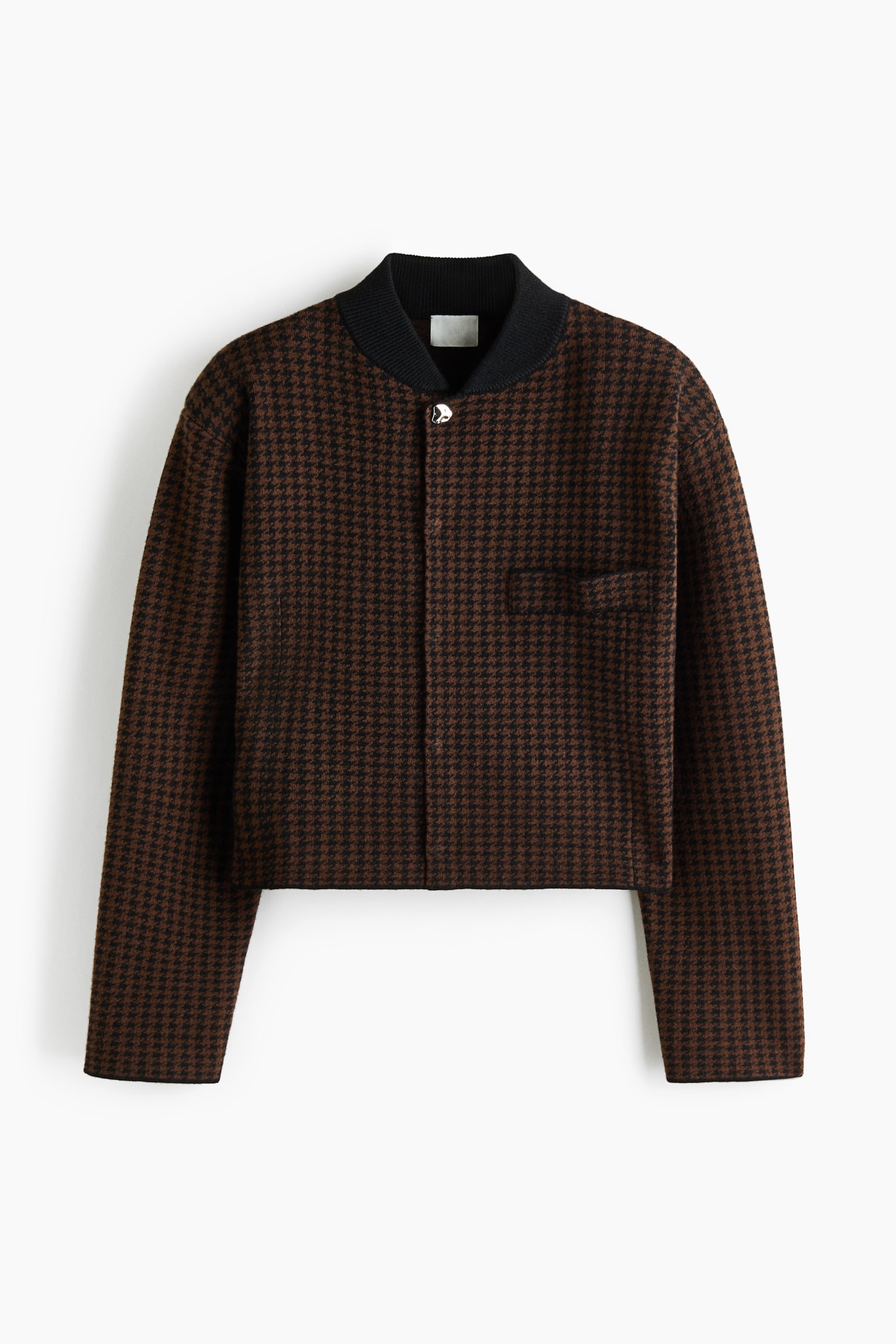 Une veste courte Ã  motif pied-de-poule marron et noir est prÃ©sentÃ©e de face, avec un col cÃ´telÃ© noir et un unique bouton argentÃ© en haut dâune patte de boutonnage dissimulÃ©e sur le devant. La veste se distingue par une silhouette boxy, des manches longues Ã  coupe droite et une seule poche passepoilÃ©e poitrine.