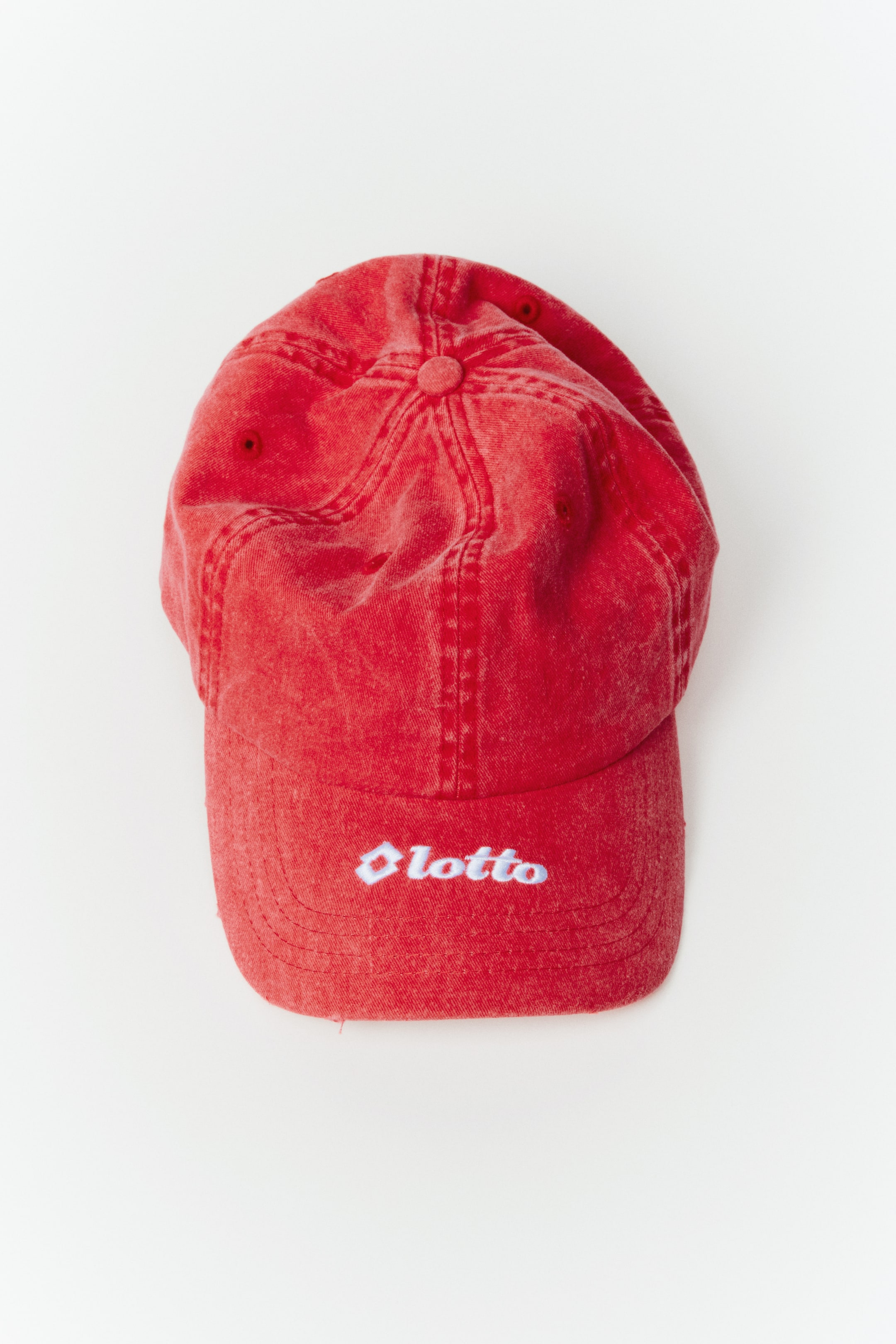 View larger image: A red baseball cap features a distressed texture and a white embroidered 'Lotto' logo on the front panel.