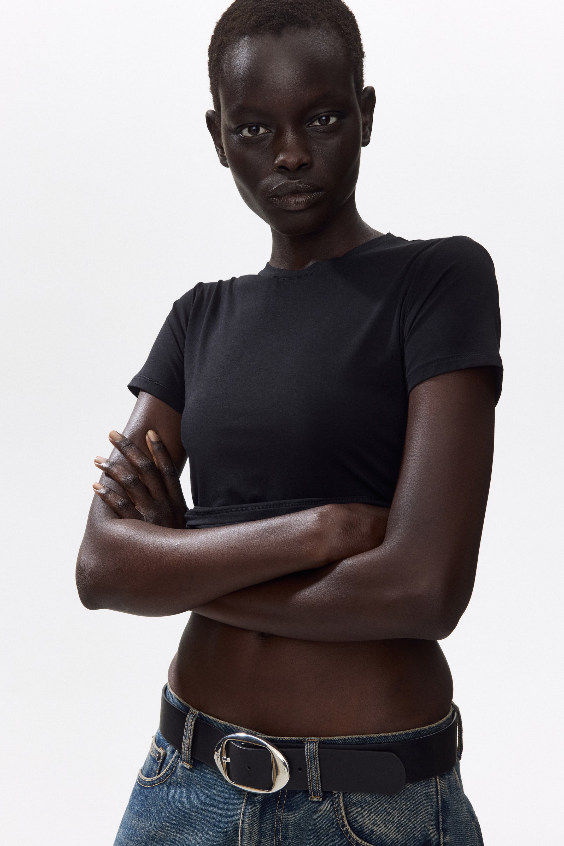 Voir une image plus grande: Un haut court noir à col rond avec des manches courtes, une silhouette ajustée et un ourlet se terminant au-dessus de la taille.