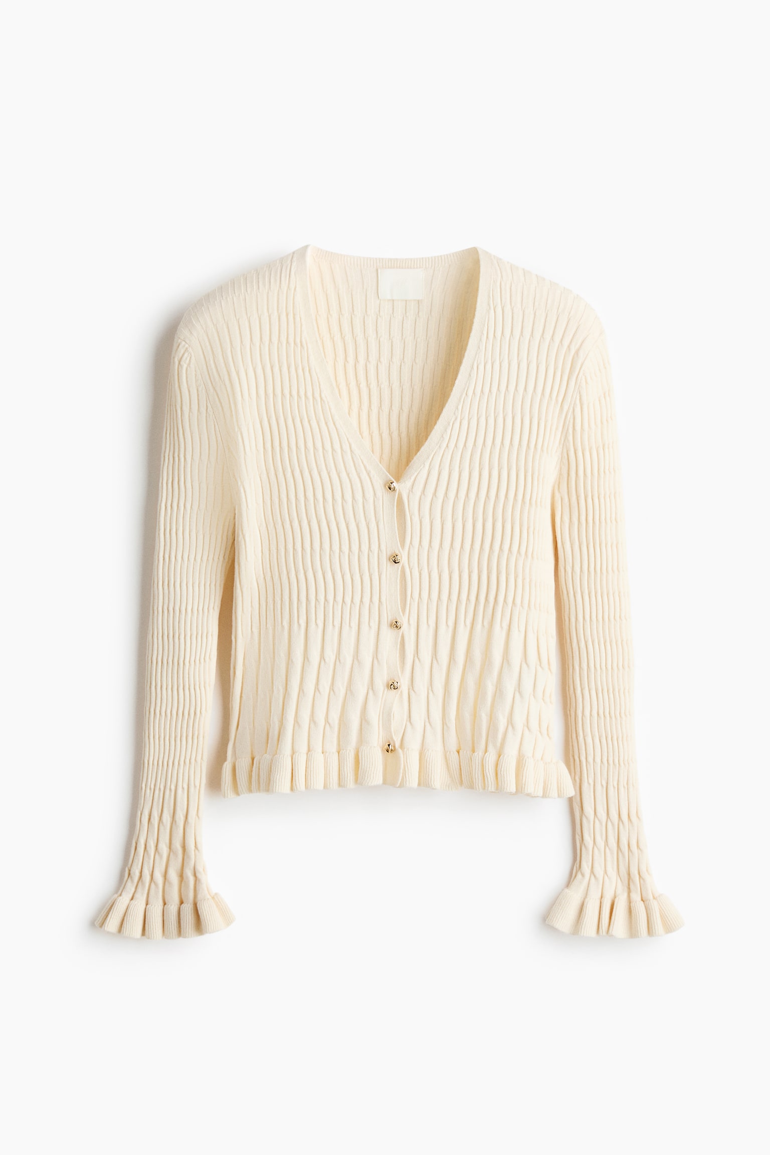 Een crÃ¨megekleurde, gemÃªleerde gebreide cardigan wordt van voren getoond, met een V-hals, lange mouwen en vijf kleine goudkleurige knopen in het midden. Het ontwerp heeft een verticaal golvend ribpatroon en is afgewerkt met verfijnde gerimpelde ruches aan de manchetten en de zoom.