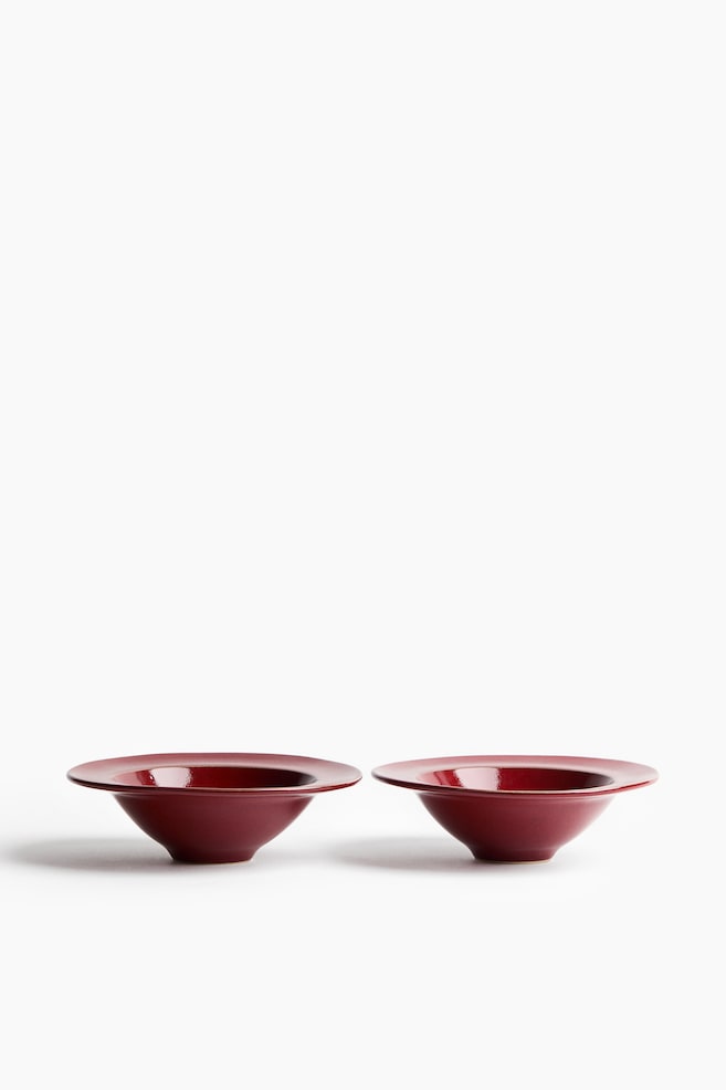 Deux bols en grès à large bord classique sont placés côte à côte, vus de face, mettant en valeur leur profil fuselé et leur finition émaillée réactive brillante dâun rouge profond. - 1
