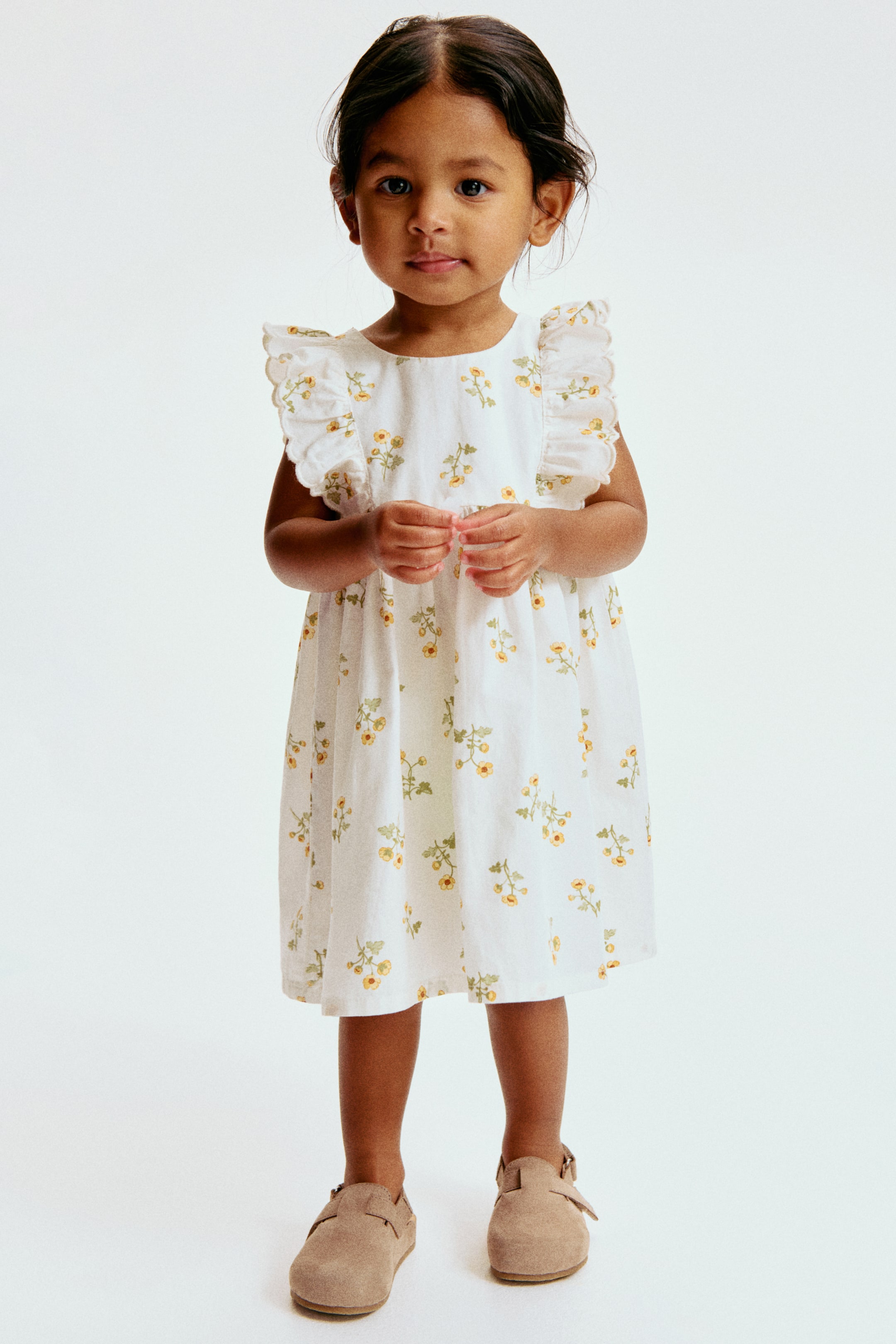 Voir une image plus grande: Une robe blanche ornée d'un motif floral jaune. Elle est conçue avec des manches à volants, un col rond et une taille froncée, offrant une coupe décontractée à hauteur du genou.