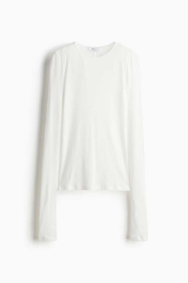 A white long-sleeve top, viewed from the front, is featuring a round neckline, long sleeves, and a relaxed fit. It is finished with a straight hem. - 1