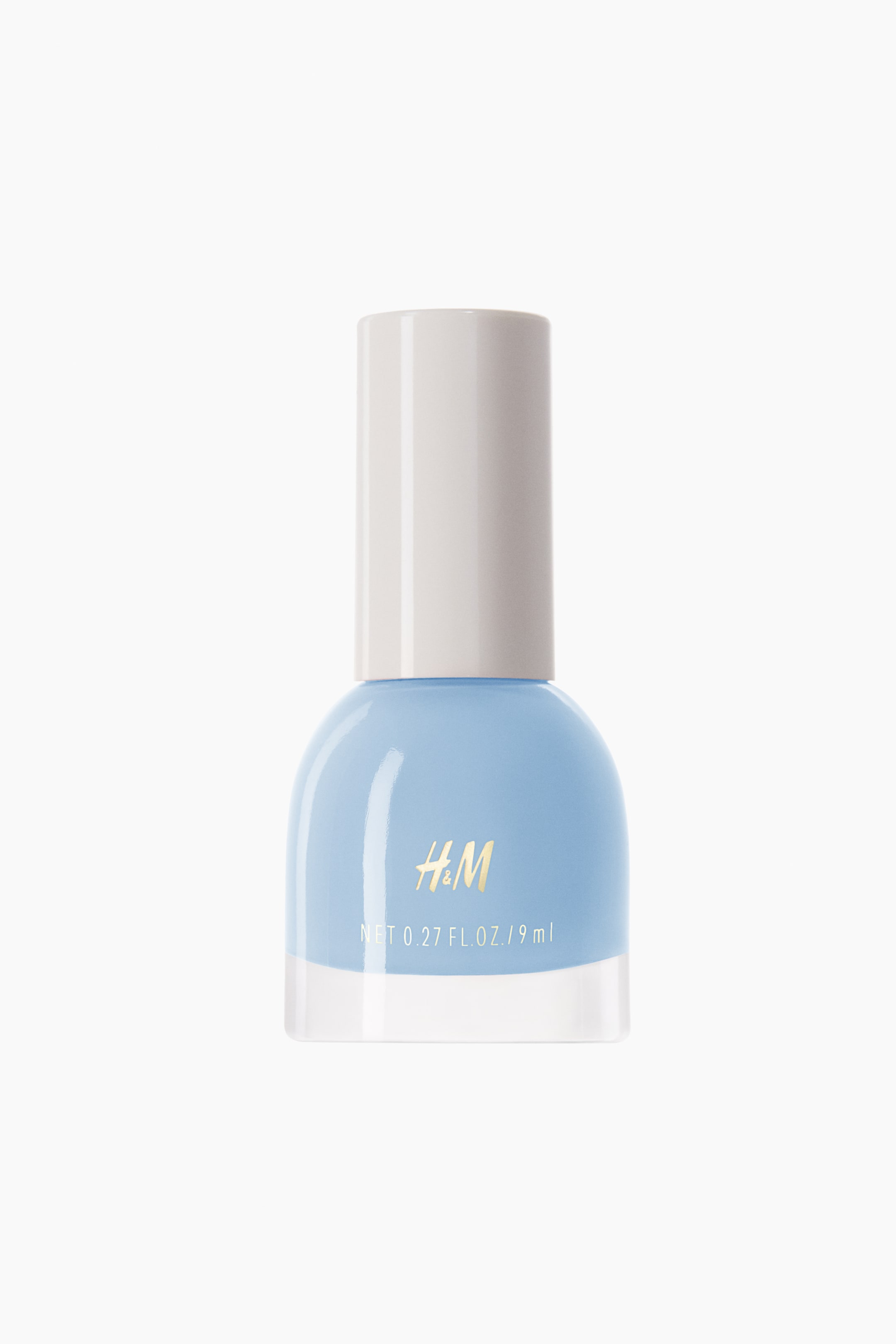 View larger image: A nail polish bottle facing forward contains a light blue polish within its transparent glass body, which features a rounded top section and a clear rectangular base. It is capped with a light beige cylindrical top, showcasing gold H&M lettering and white volume details on the front.