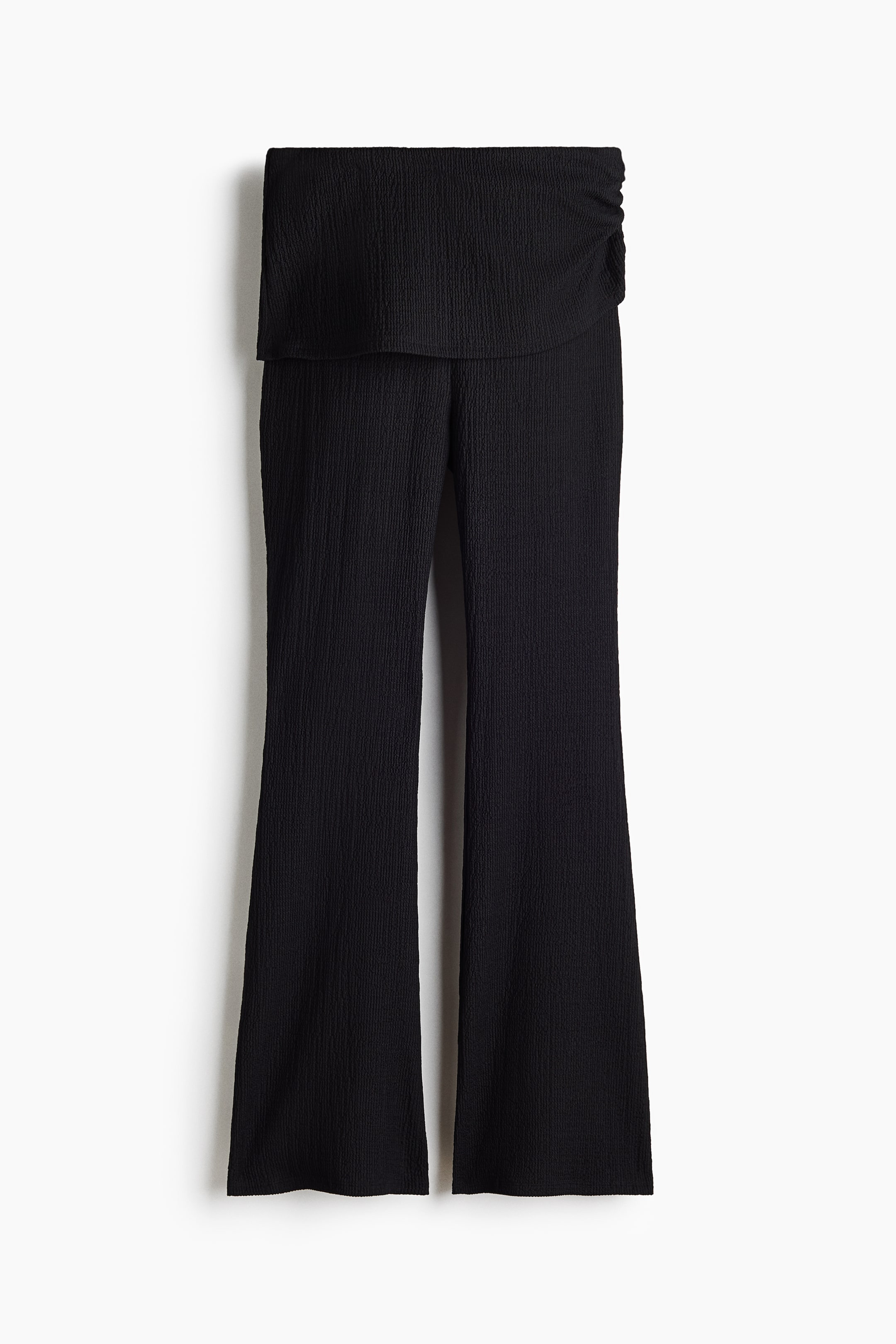 View larger image: Black pants crafted from textured crinkle fabric, showcasing a wide fold-over waistband with ruching on the right side, and a bootcut silhouette.