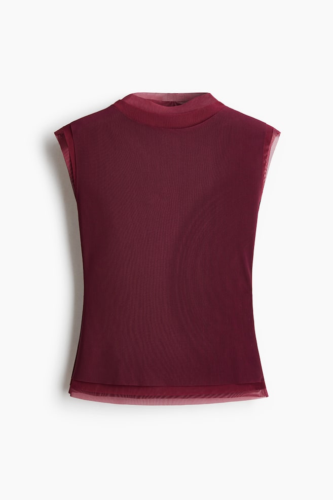 A burgundy sleeveless top is shown from the front, featuring a mock neck and a double-layered design, with a sheer mesh underlayer extending slightly beyond the opaque main fabric at the neckline, armholes, and hem. - 1