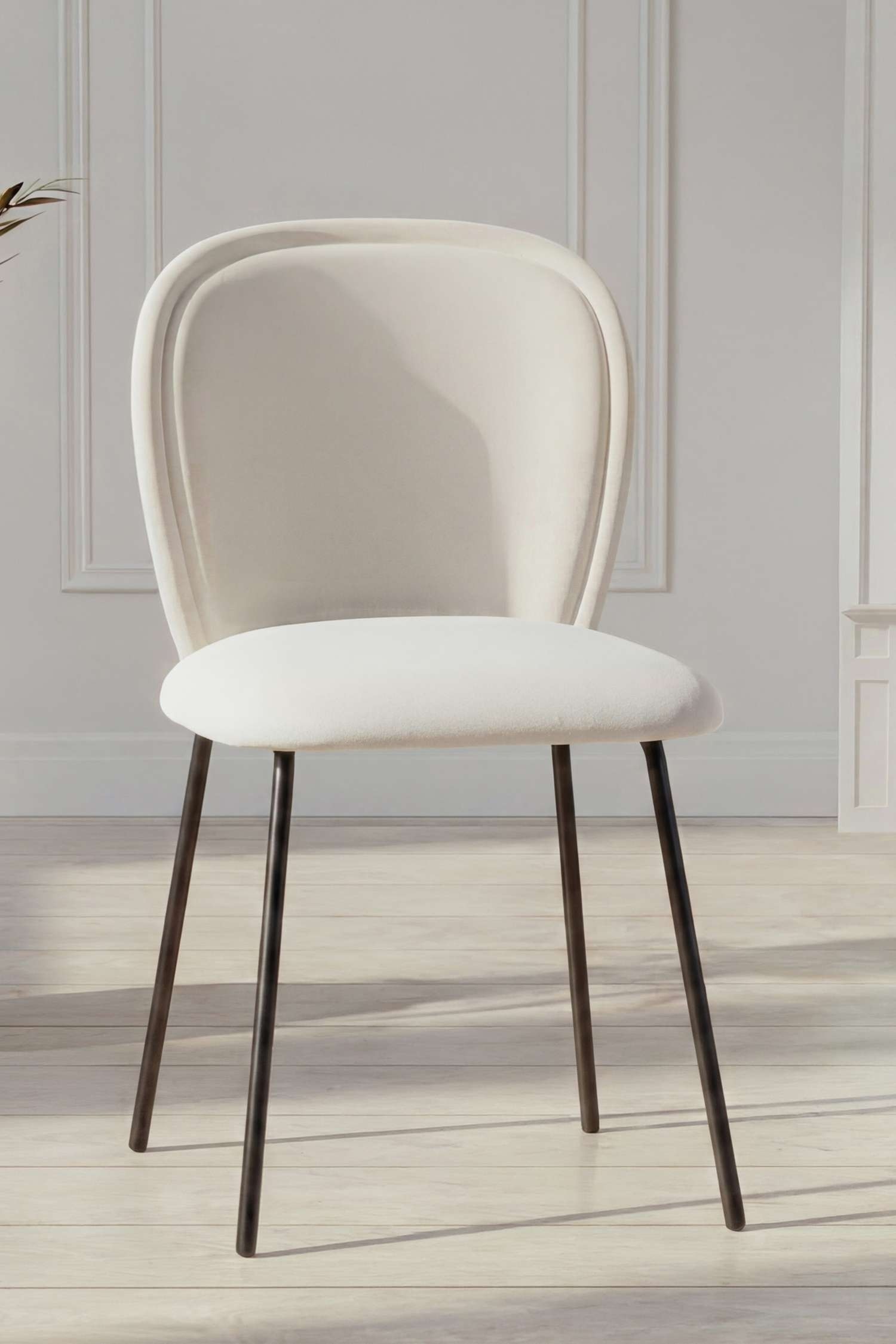 Ein Stuhl ist nach vorne gerichtet und verfügt über eine cremefarbene, gepolsterte Rückenlehne mit abgerundetem oberen Ende sowie einen passenden gepolsterten Sitz. Er wird von vier schlanken, schwarzen Metallbeinen getragen.