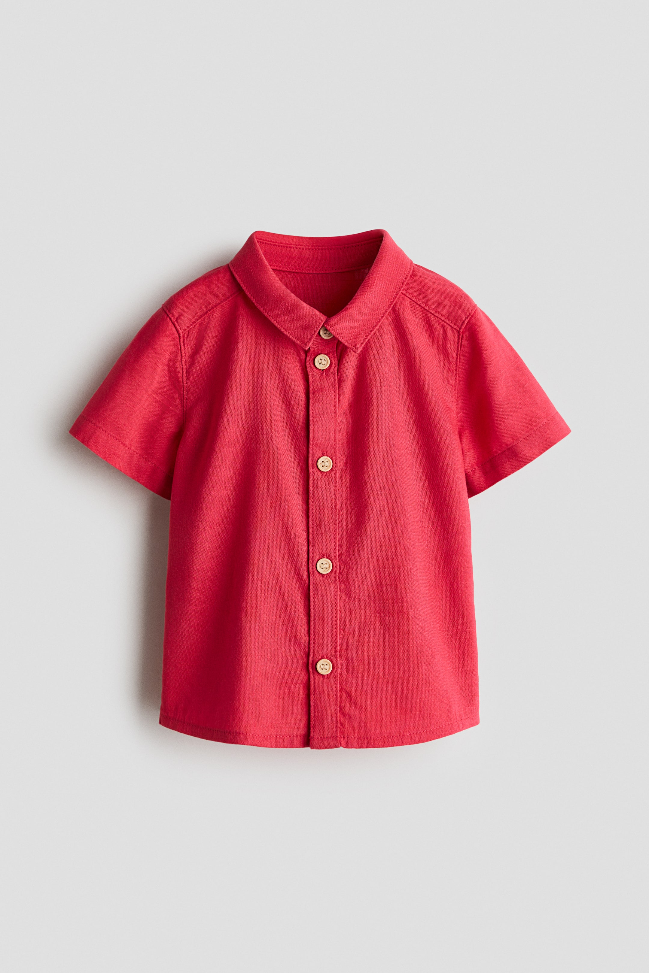 View larger image: A red short-sleeved shirt in crisp cotton poplin is shown from the front. It features a turn-down collar, buttons running down the front, and a gently rounded hem.