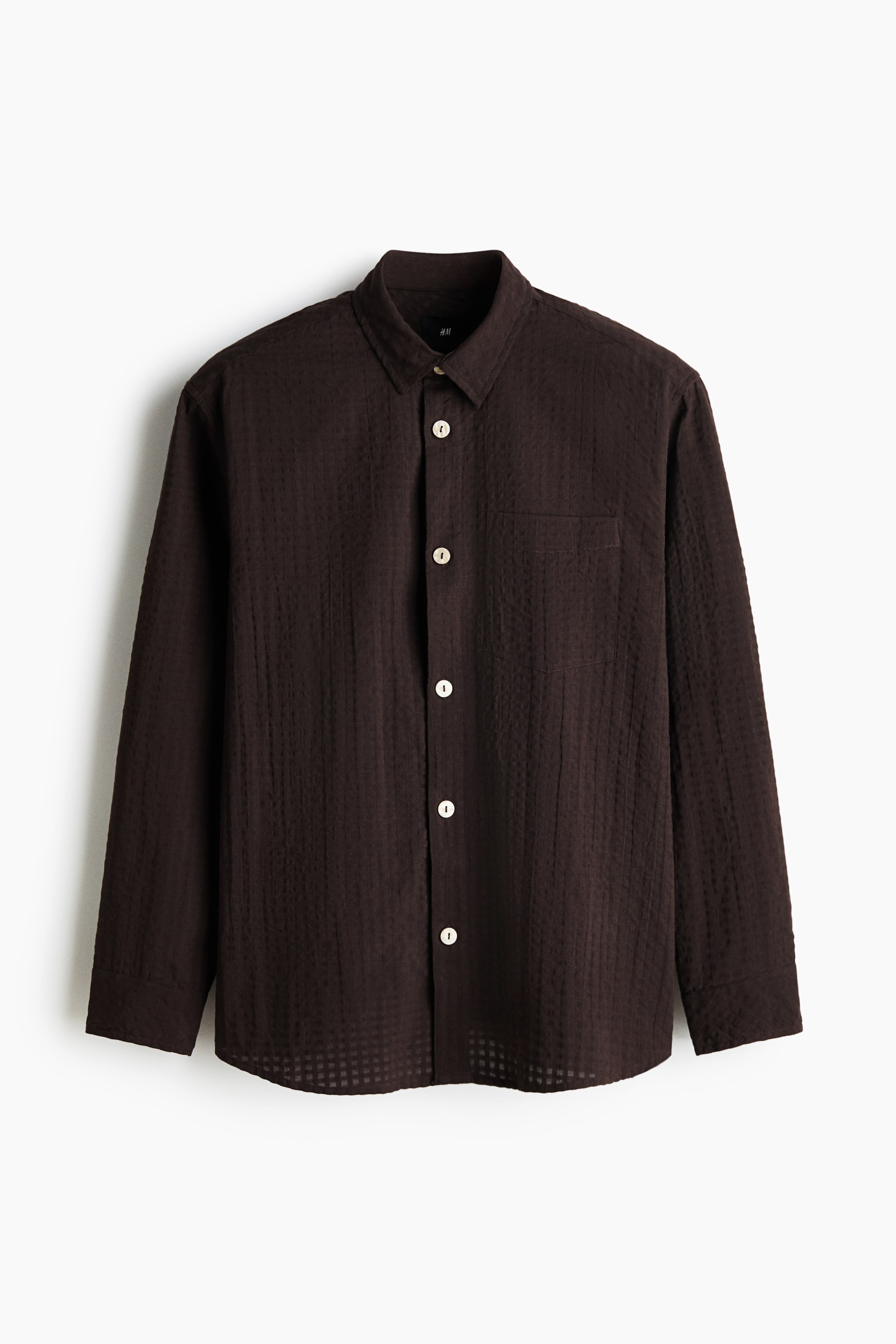 View larger image: A dark brown seersucker shirt is presented in its front view, featuring a turn-down collar, a button-down front with light-coloured buttons, a patch chest pocket, long sleeves with buttoned cuffs, and a gently rounded hem.
