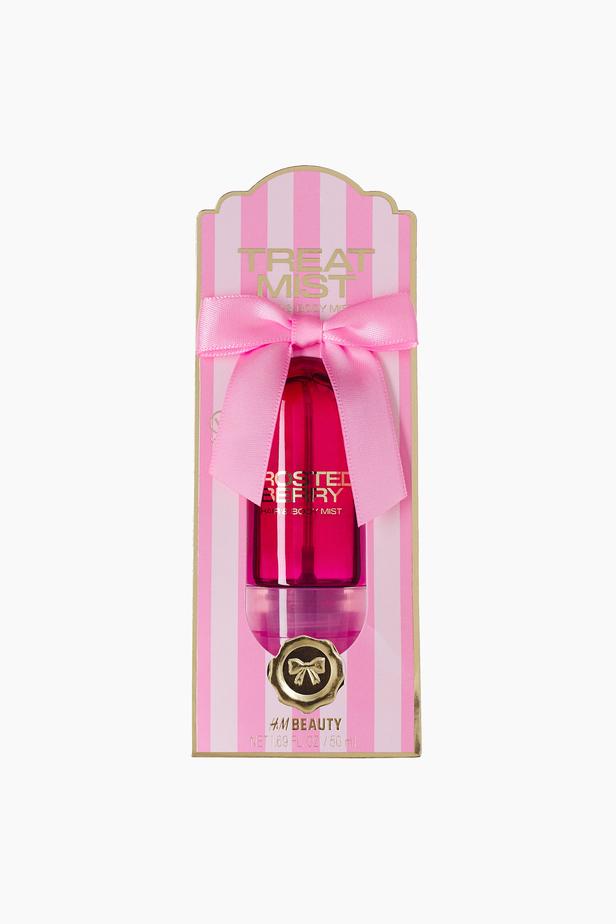 View larger image: A hair and body mist is displayed in a front-facing view, featuring a translucent magenta, capsule-shaped bottle mounted on a pink-and-white striped backing card. The packaging showcases a large pink satin bow tied around the bottle, which features gold lettering and is decorated with a gold-foiled seal and text at the bottom.