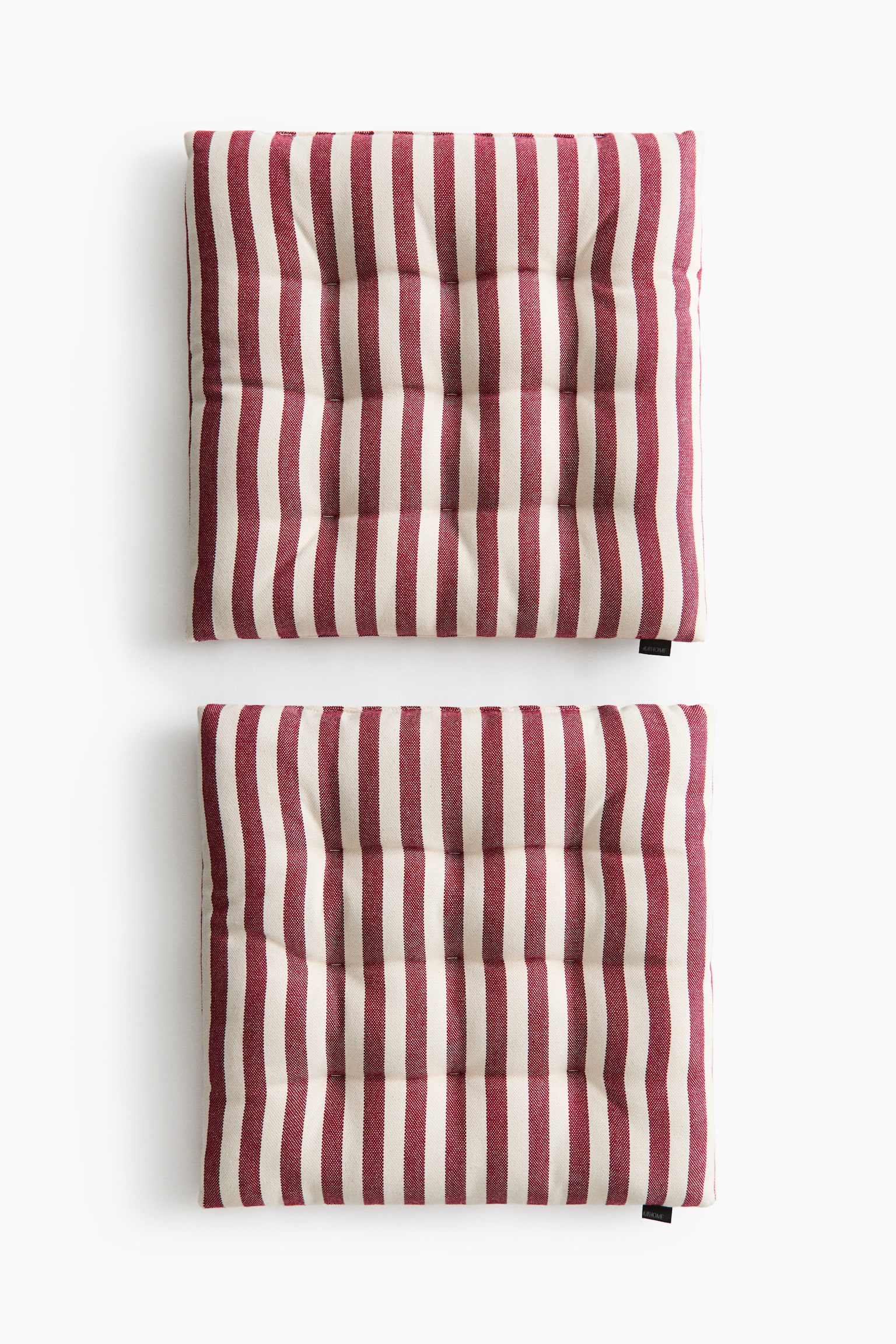 Two square padded seat cushions are shown from a front overhead view, featuring a vertical striped pattern in dark red and off-white. The cushions display evenly spaced tufted quilt knots across their surfaces to help maintain their shape. - 1