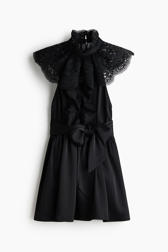 Ein schwarzes Kleid mit einem hohen, gerüschten Spitzenkragen und einem aufwendigen Spitzendesign, das sich über die Schultern erstreckt. Die Taille wird von einer markanten Satinschleife betont, und der Rock fließt in eine ausgestellte Silhouette. - 1
