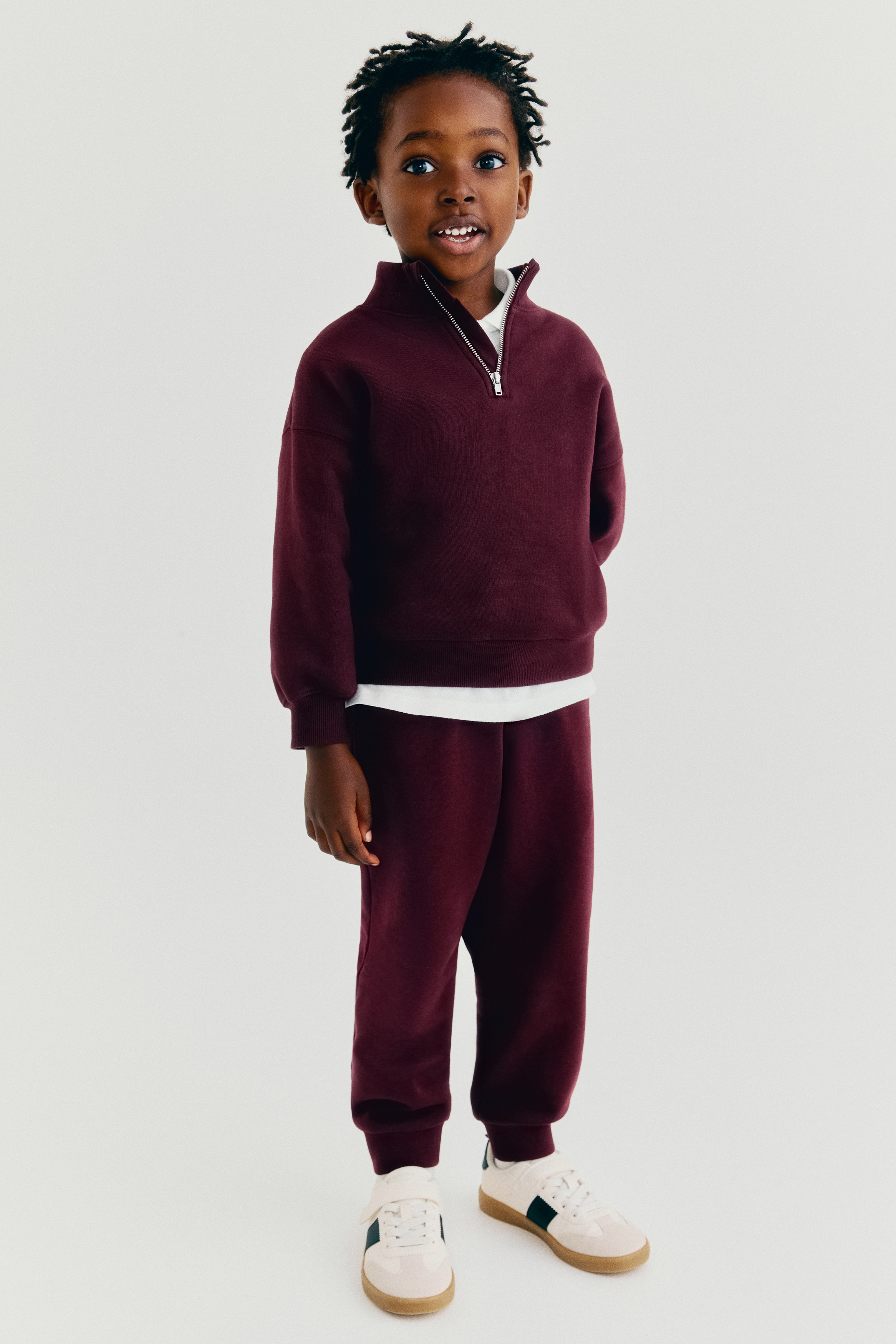 Maroon sweatpants are displaying from the front, featuring an elasticated waistband with a drawstring and ribbed cuffs.
