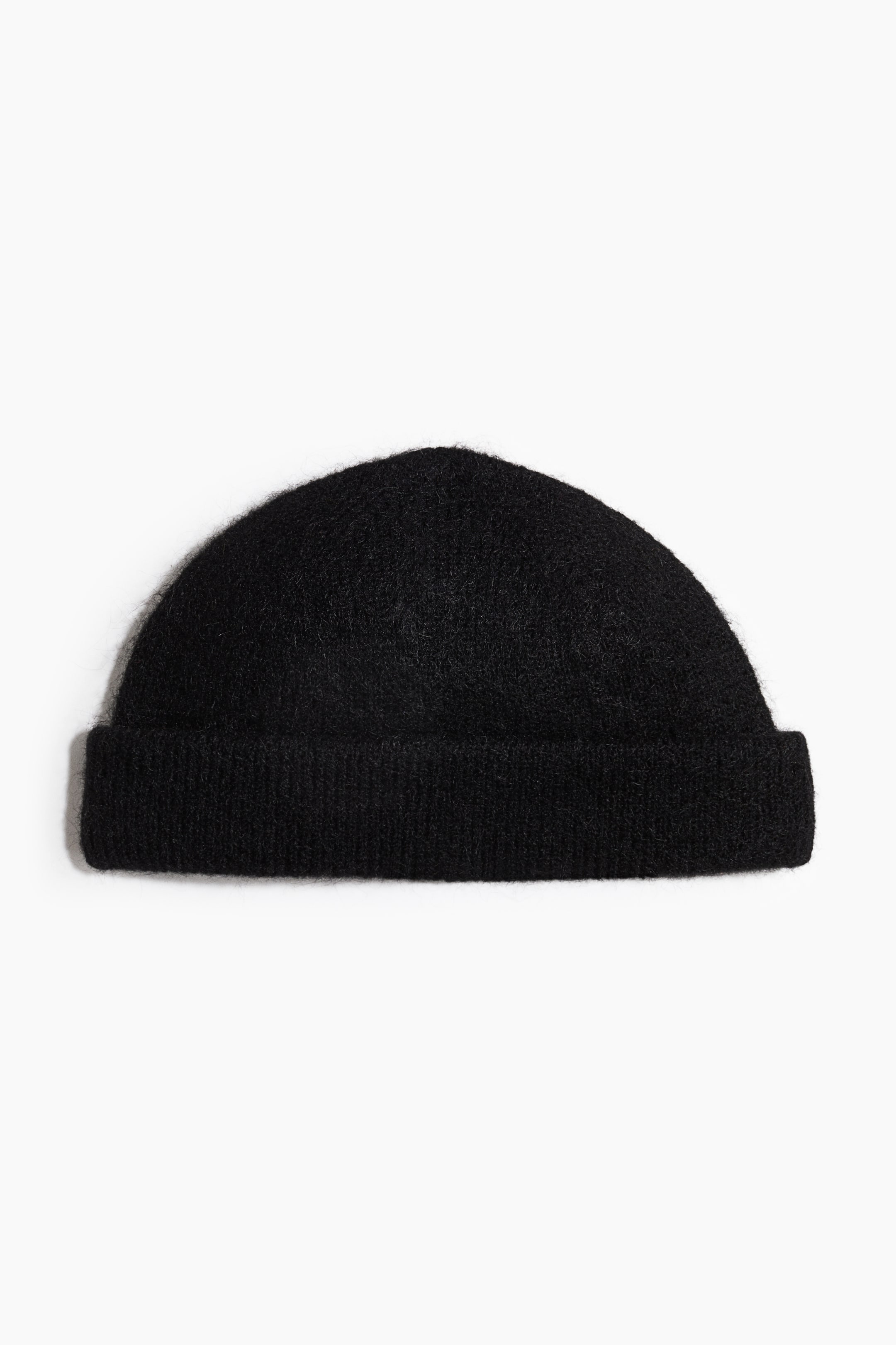 View larger image: A black knit beanie is shown facing forward, featuring a rounded crown and a thick folded cuff. The beanie has a fuzzy, brushed texture with soft, visible fibers.