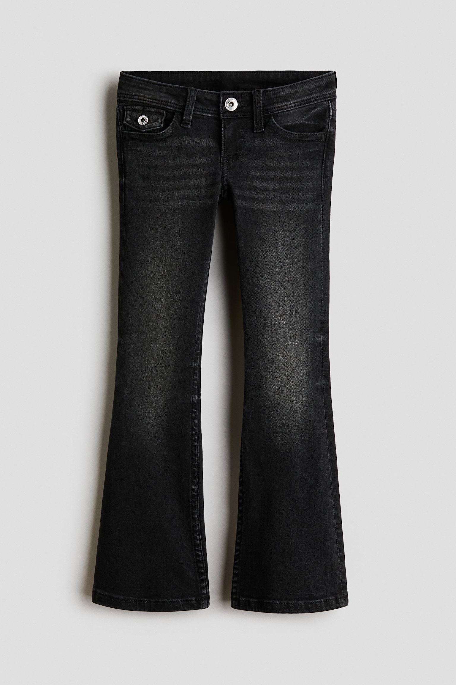 Eine schwarze, gewaschene Denim-Jeans wird von vorne gezeigt und verfÃ¼gt Ã¼ber einen tief sitzenden Bund mit Knopfverschluss und GÃ¼rtelschlaufen. Die Jeans sitzt an HÃ¼fte und Oberschenkeln schmal an und weitet sich dann zu ausgestellten Beinen.