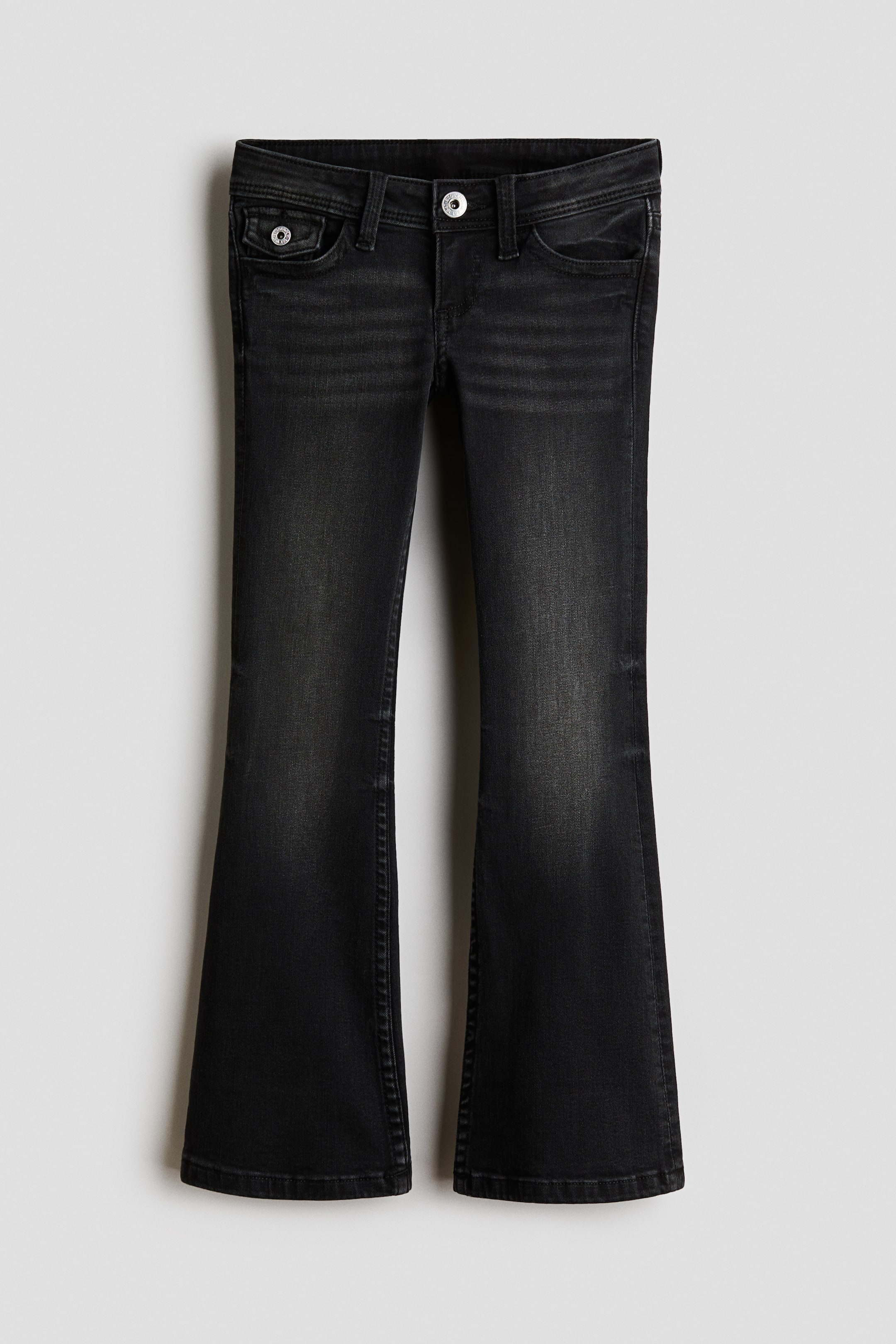 Grotere afbeelding bekijken: Een zwarte gewassen denim jeans wordt van voren getoond, met een lage taille met knoopsluiting en riemlussen. De jeans heeft een slim fit rond de heupen en dijen en loopt vervolgens uit in uitlopende pijpen.