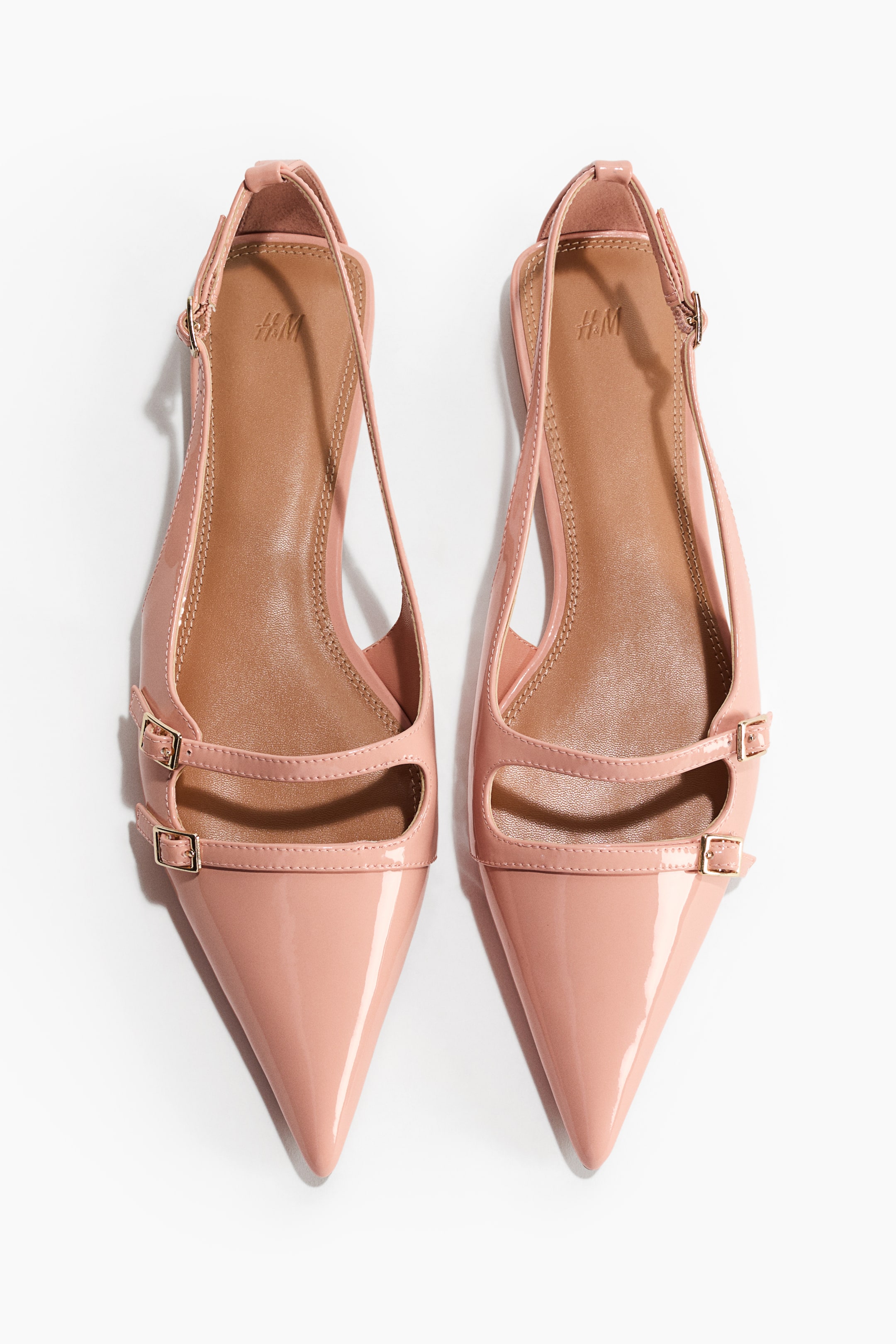 Agrandir l'image: Slingbacks, vus de FACE, présentent une finition vernie rose clair, des bouts pointus et des brides étroites réglables autour du talon. Deux brides supplémentaires étroites avec de petites boucles dorées croisent le dessus du pied.
