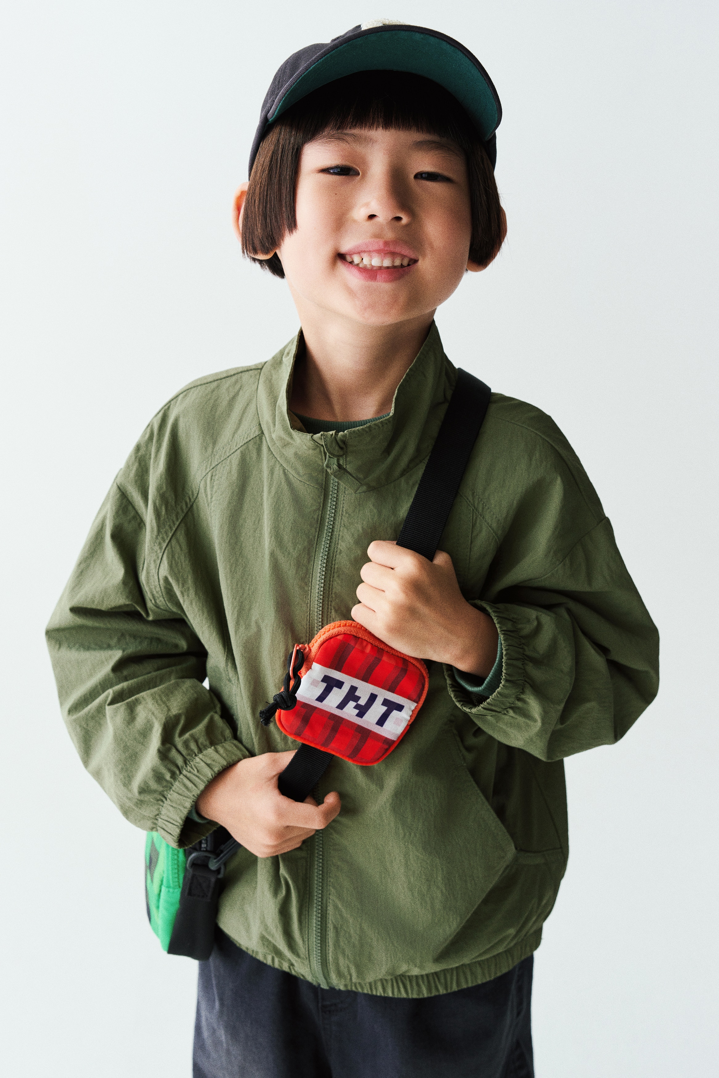 Má»t chiáº¿c Ã¡o khoÃ¡c giÃ³ nylon mÃ u xanh lÃ¡ ÄÆ°á»£c chá»¥p á» máº·t trÆ°á»c, vá»i cá» Äá»©ng, khÃ³a kÃ©o phÃ­a trÆ°á»c dÃ i toÃ n thÃ¢n, vÃ  pháº§n vai xuÃ´i vá»i ÄÆ°á»ng may raglan. Ão hiá»n thá» cÃ¡c ÄÆ°á»ng may cong á» thÃ¢n trÆ°á»c, tÃºi chÃ©o, vÃ  pháº§n chun bá»c táº¡i cá» tay Ã¡o cÃ¹ng gáº¥u Ã¡o.