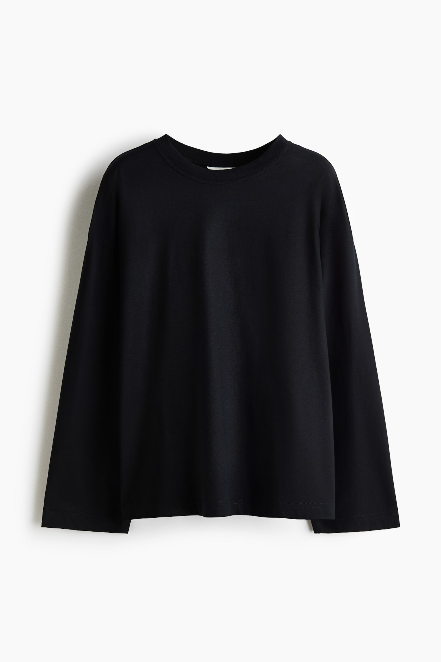 Ein schwarzes Langarm-T-Shirt hÃ¤ngt mit der Vorderseite nach vorne und zeigt eine lockere Passform mit Ã¼berschnittenen Schultern und einem klassischen Rundhalsausschnitt. Das KleidungsstÃ¼ck verfÃ¼gt Ã¼ber weite, gerade geschnittene Ãrmel und einen klaren, geraden Saum.