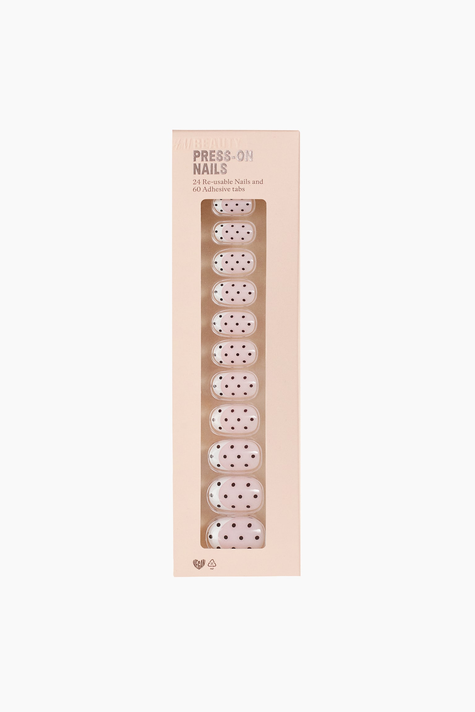 Shown from the front, a rectangular light pink package displays press-on nails through a clear vertical window. The visible nails feature a light pink base decorated with black polka dots and a white crescent detail at the base. - 1