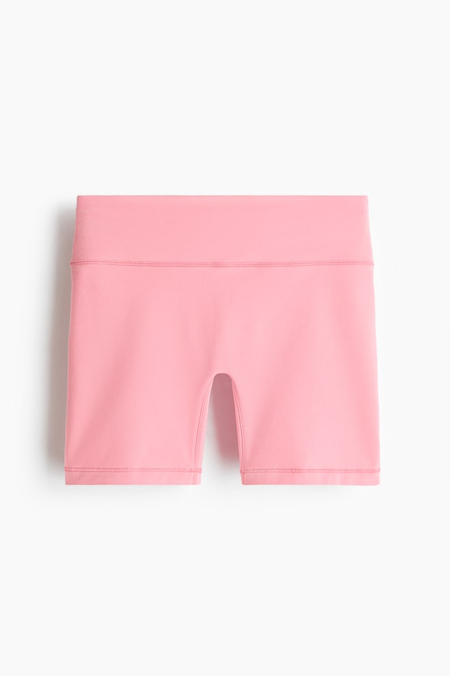 Shorts de sport roses orientés vers l'avant, avec une large ceinture haute et des jambes courtes et ajustées avec des coutures visibles le long des ourlets. - 1