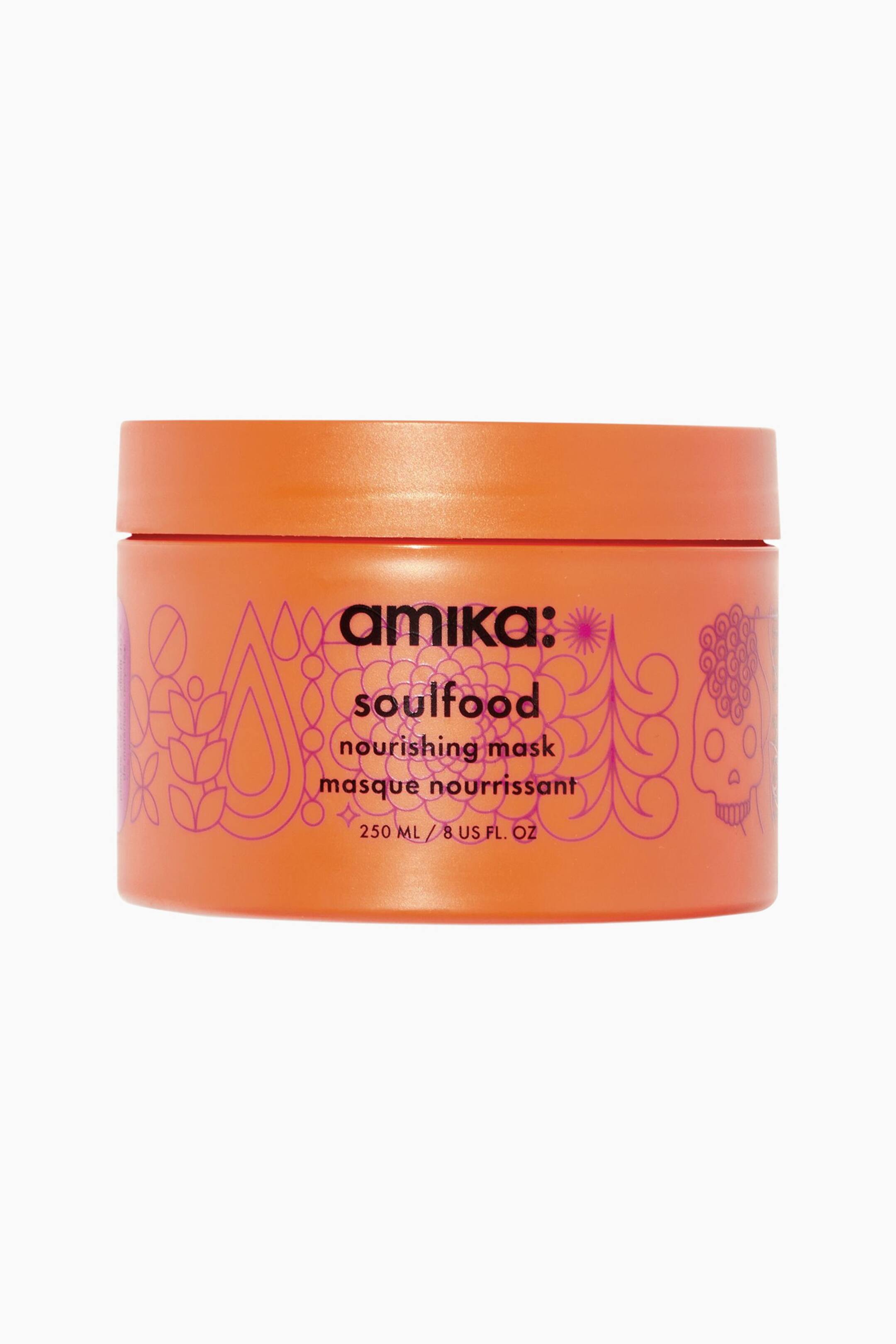 Visa större bild: Amika Soulfood Nourishing Mask står vänd framåt och har en cylindrisk orange burk med ett matchande skruvlock. Förpackningen visar intrikata rosa linjegrafikdetaljer som omger svart text med orden ”amika: soulfood nourishing mask.”