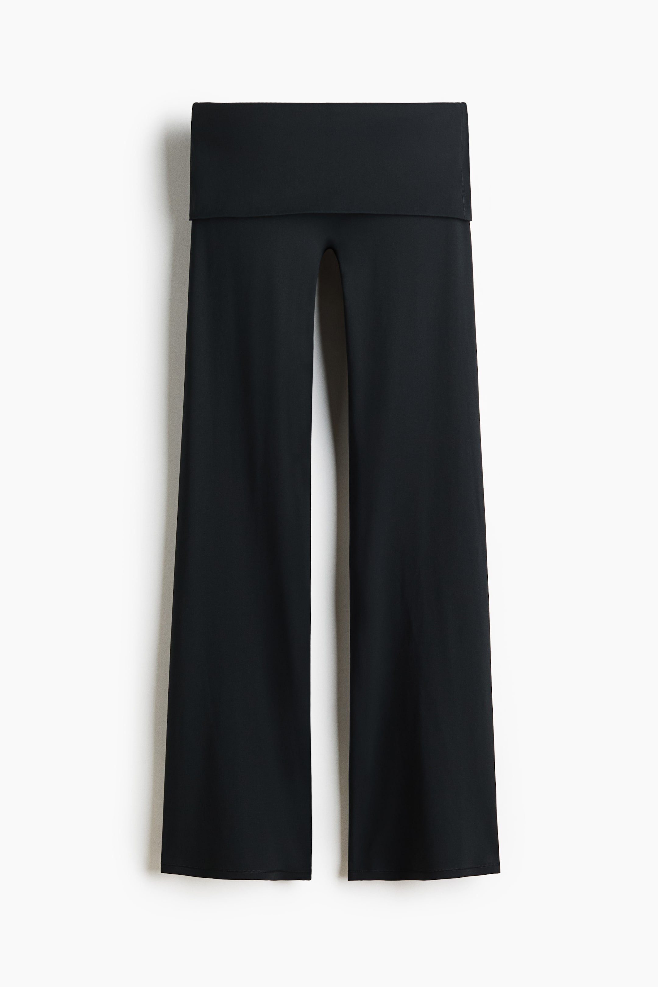 הצגת תמונה גדולה יותר: מכנסיים שחורים תלויים ומוצגים מקדימה, עם חגורת מותן רחבה מקופלת ורגליים רחבות וישרות עם שוליים פשוטים.