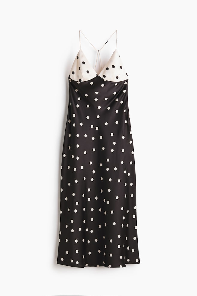 A slip dress is presenting FRONT, featuring a black body with white polka dots and a contrasting cream bodice with black polka dots. It is displaying a V-neckline and thin spaghetti straps that are crossing at the back, and is falling to a midi length. - 1