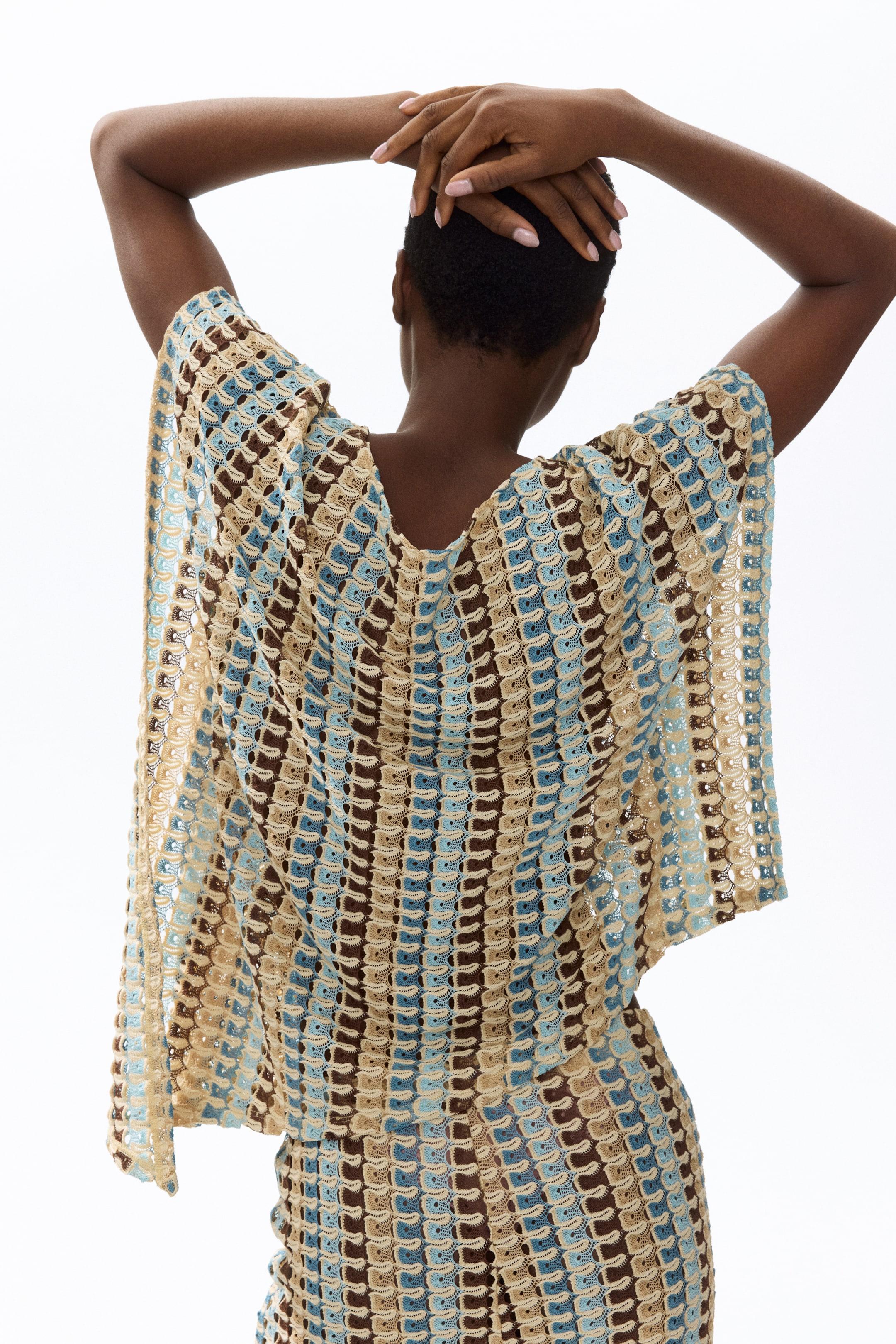 View larger image: This ensemble features a coordinated knitted top and form-fitting bottom, displayed from the back to highlight an open-knit scallop pattern. The design includes wide sleeves, a broad back neckline, and alternating stripes in hues of light beige, light blue, and dark brown.