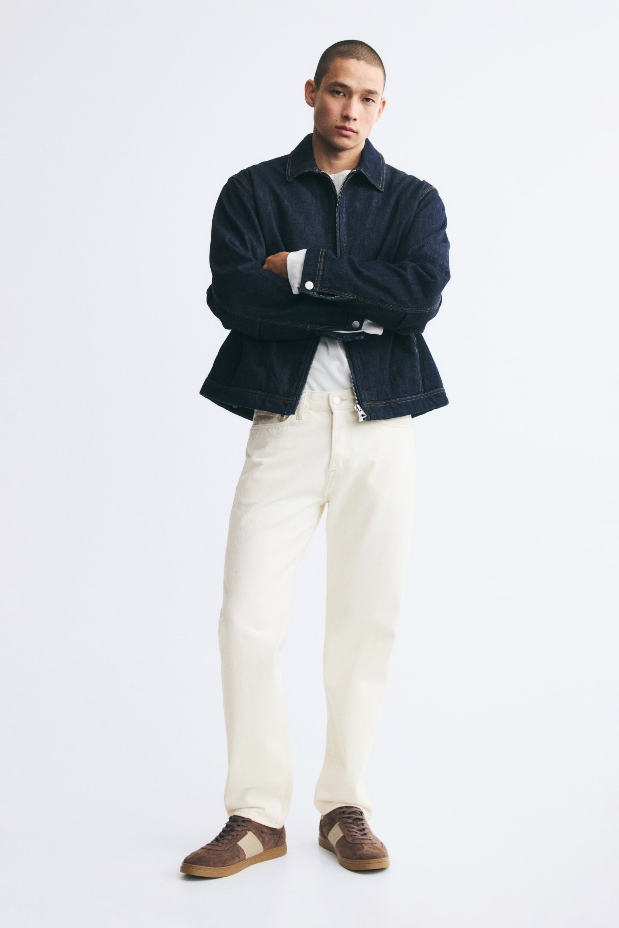 Visualizza immagine più grande: Jeans in denim bianco sporco a cinque tasche, dal taglio dritto, indossati dalla modella. I jeans regular fit sono abbinati a una giacca in denim scuro con zip sopra una t-shirt bianca e sneakers marroni.