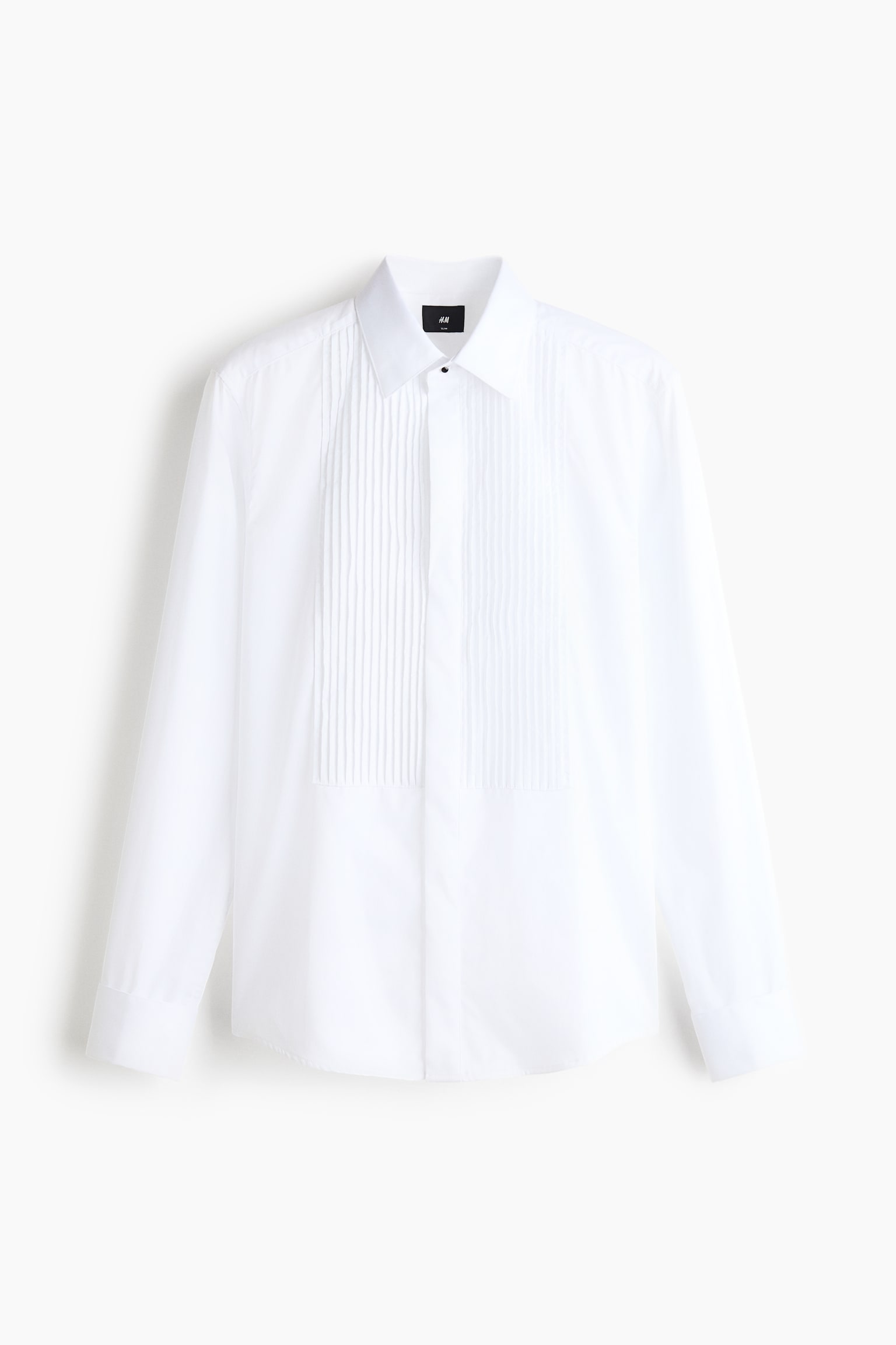 A white tuxedo shirt is presented front-facing, showcasing a classic spread collar and a pintuck-pleated bib on the chest. The shirt features a concealed button placket with a single visible black top button, long sleeves with simple cuffs, and a slightly curved hemline.