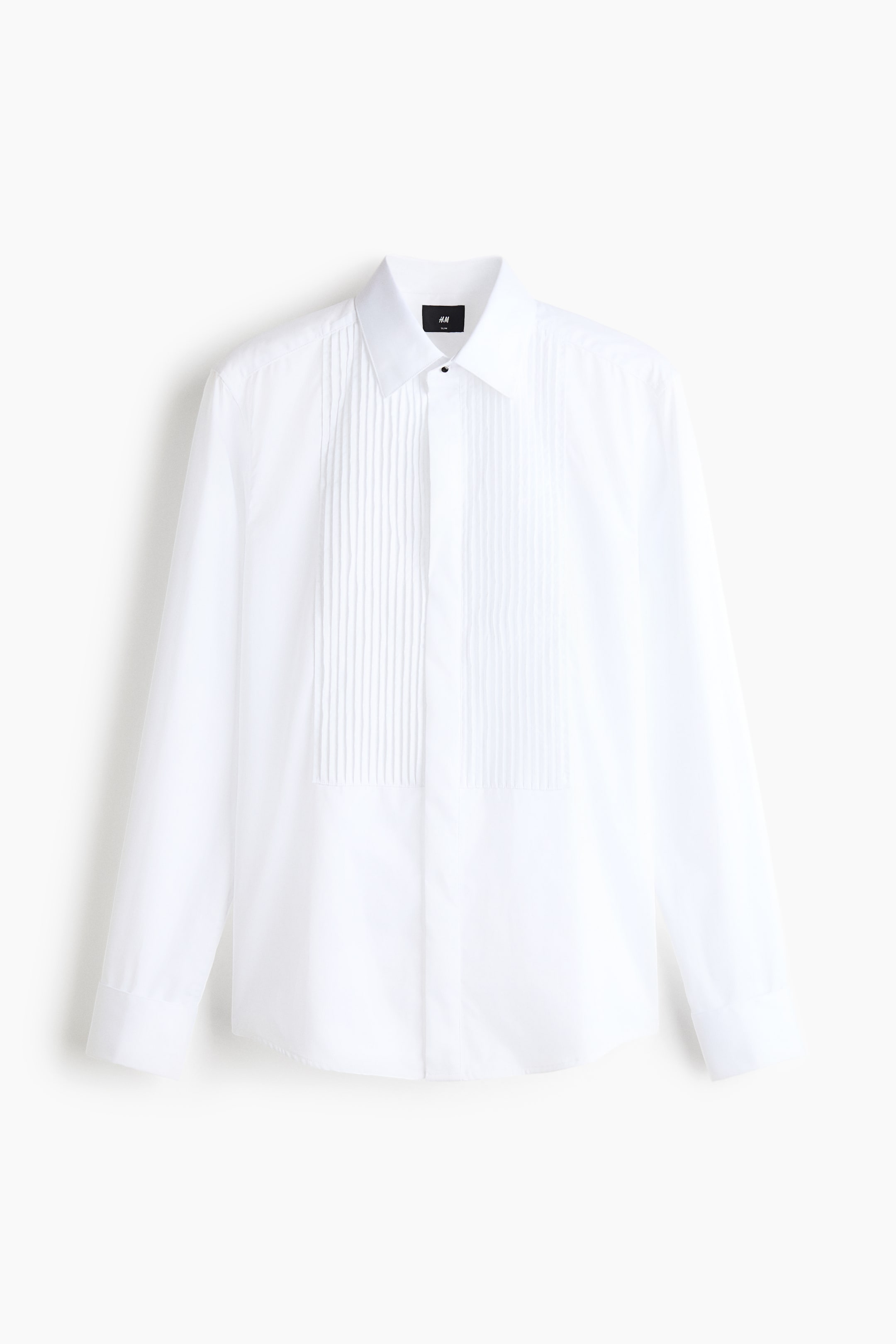 Ver imagen más grande: Una camisa de esmoquin blanca vista de frente, que muestra un clásico cuello italiano y un peto en el pecho con pliegues pintuck. La camisa presenta una botonadura oculta con un único botón negro visible en la parte superior, mangas largas con puños sencillos y un bajo ligeramente curvado.
