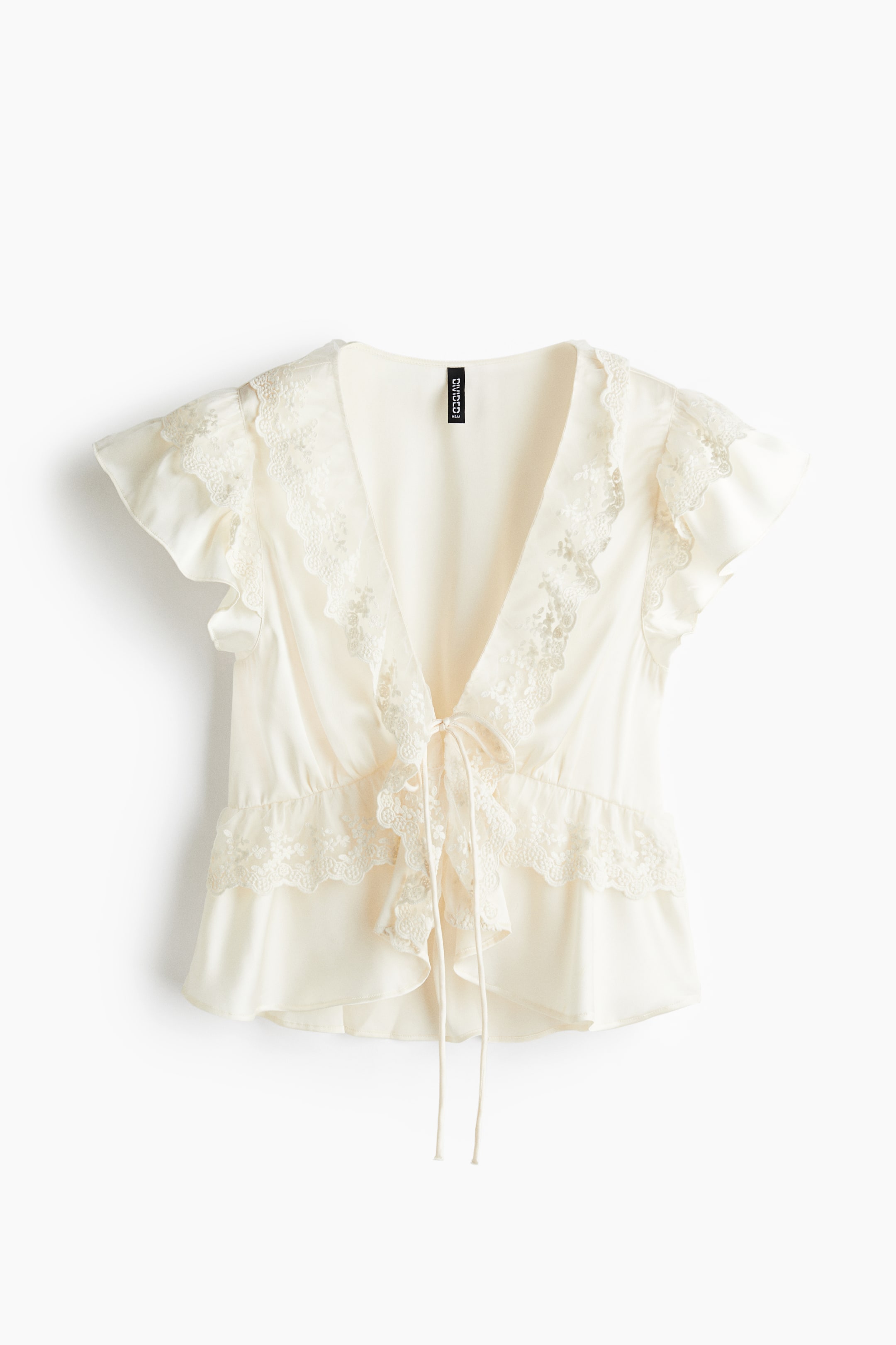 View larger image: An off-white short-sleeved top is presenting its front, featuring a deep V-neckline and ruffled flutter sleeves, both edged with delicate lace trim. A ribbon is tying at the waist, creating a gathered effect and a ruffled peplum hem, also adorned with lace.