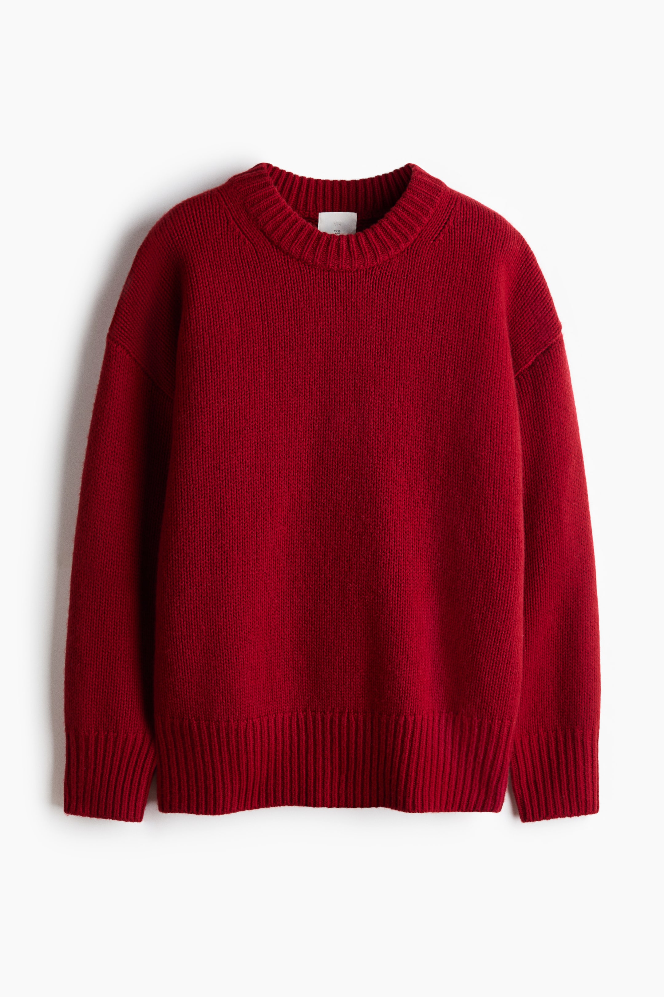 Ampliar la imagen: Se muestra un suéter tejido rojo de corte oversized, visto de frente, con un cuello redondo acanalado y grueso, hombros caídos y mangas largas. El diseño se completa con puños anchos acanalados y un dobladillo acanalado a juego.