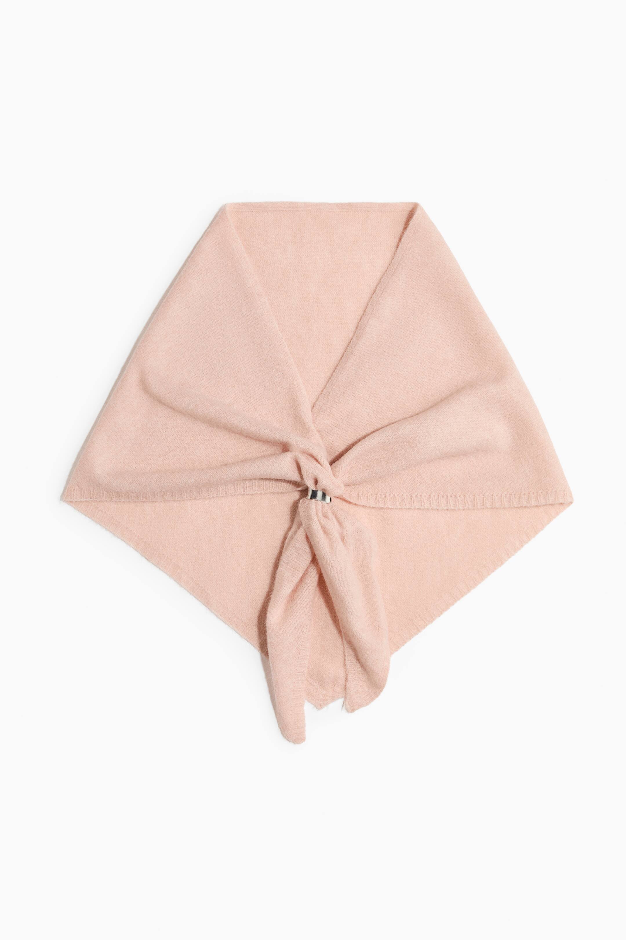 View larger image: A pale pink knit scarf is laid flat in a diamond shape, showing a soft, fine-knit texture. The fabric is gathered at the centre through a small, silver-toned ring, with two loose ends draping downwards.