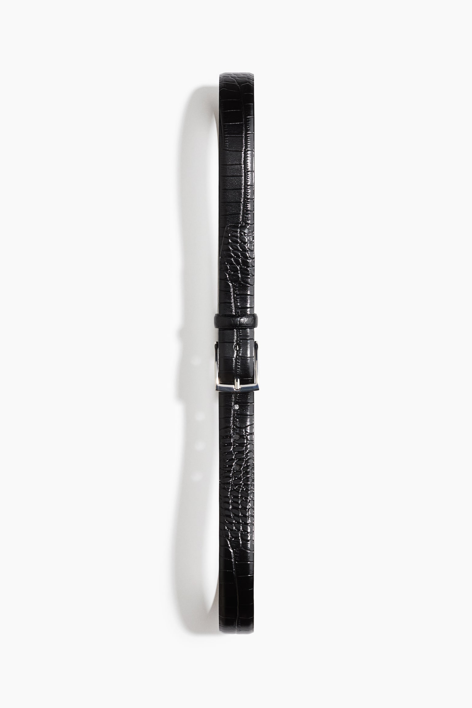 Un cinturón de cuero negro con textura en relieve de cocodrilo se extiende verticalmente en vista frontal, sujetado con una hebilla metálica cuadrada de tono plateado y una trabilla a juego de cuero.